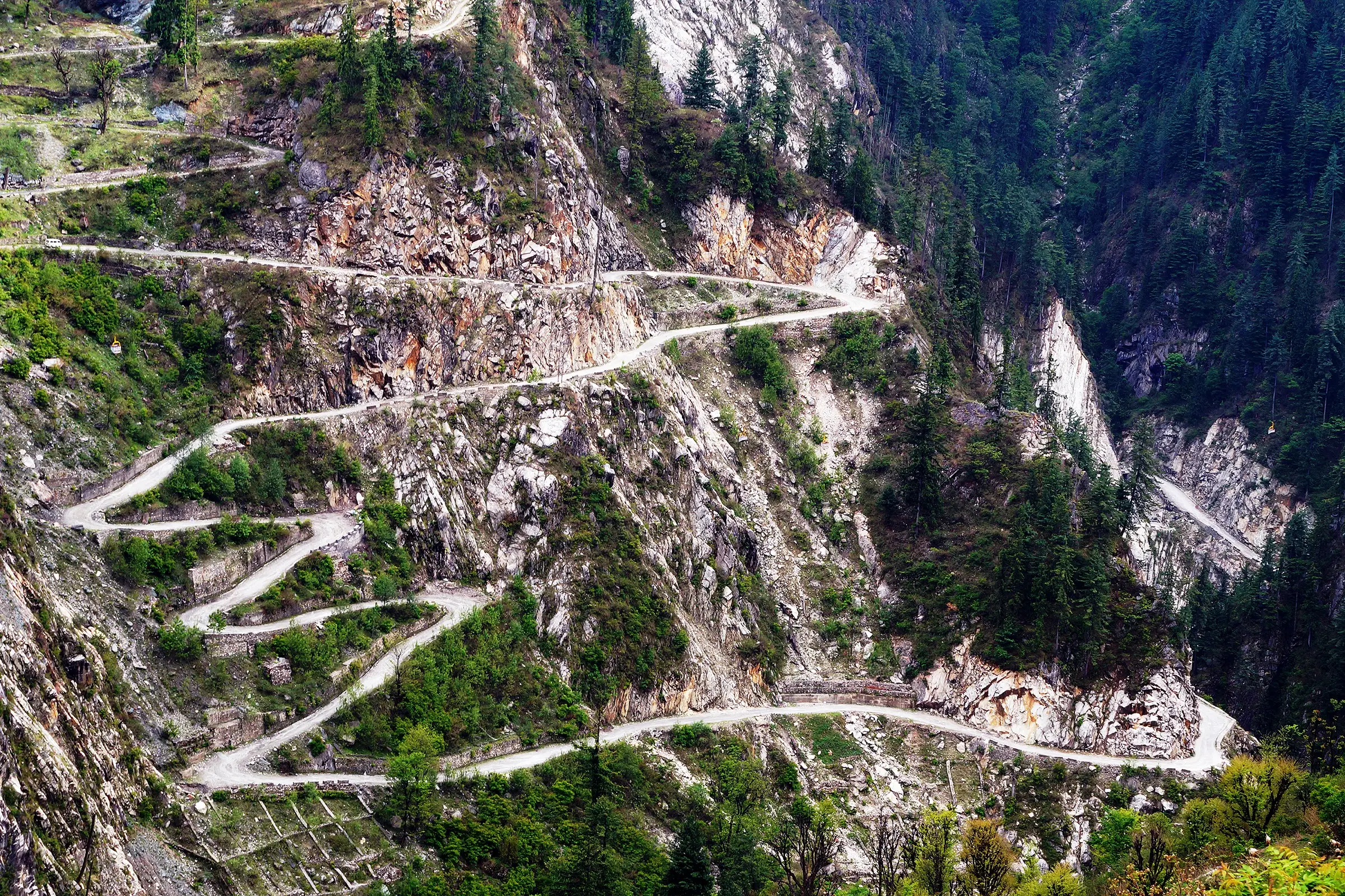Zigzag road cut into the cliffs of the Malana valley, seen from Malana village near the start of the trek