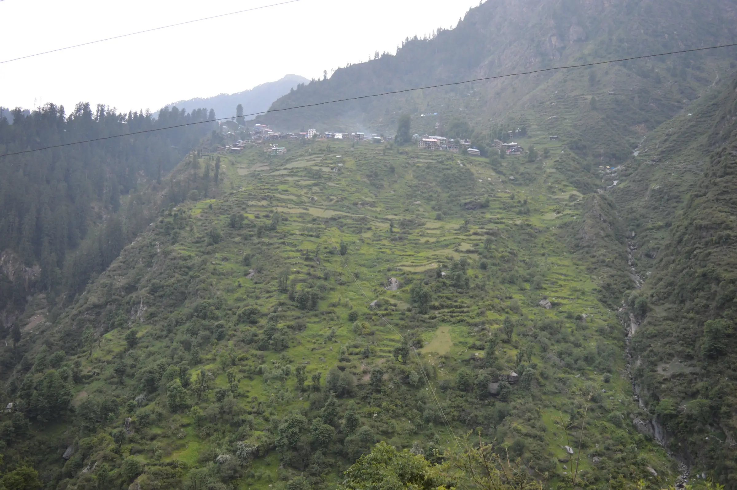 Malana village seen across the valley, perched at the top of steep terraced slopes