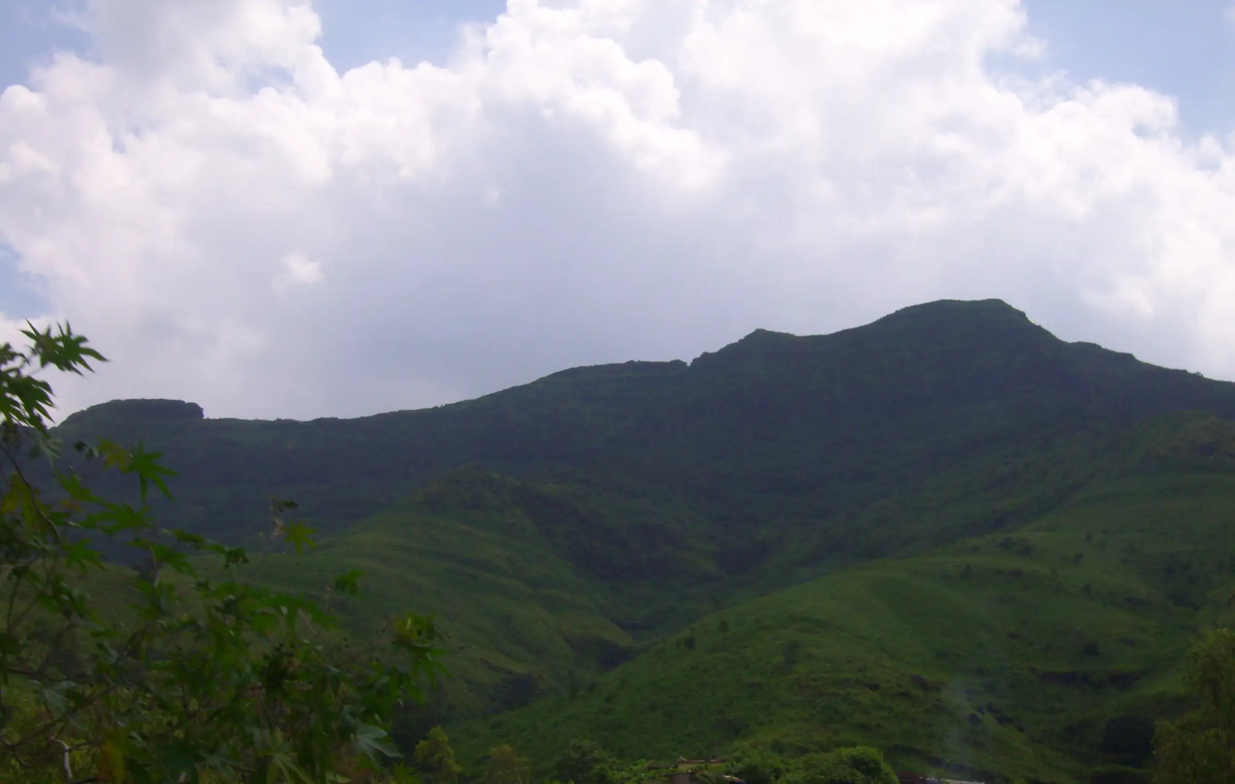 Green monsoon hills of the Purandar range under a sky full of white clouds