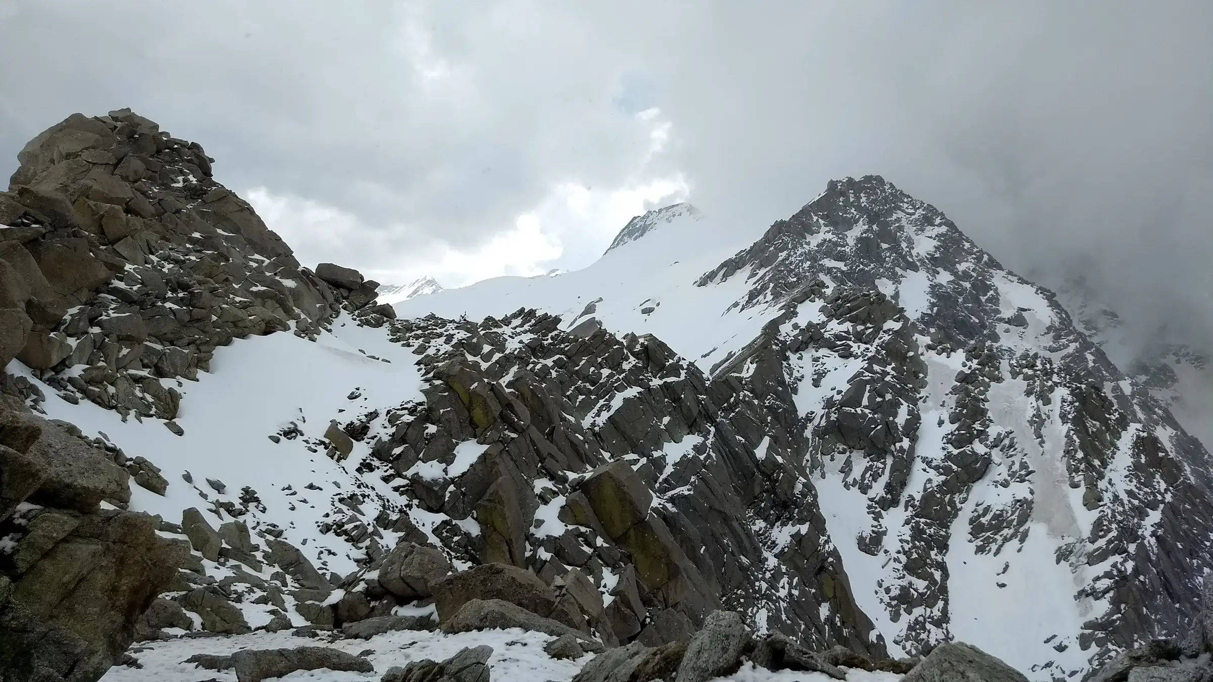 Snow-streaked rocky summit of Moon Peak rising on the right above the Indrahar Pass ridge in the Dhauladhar range