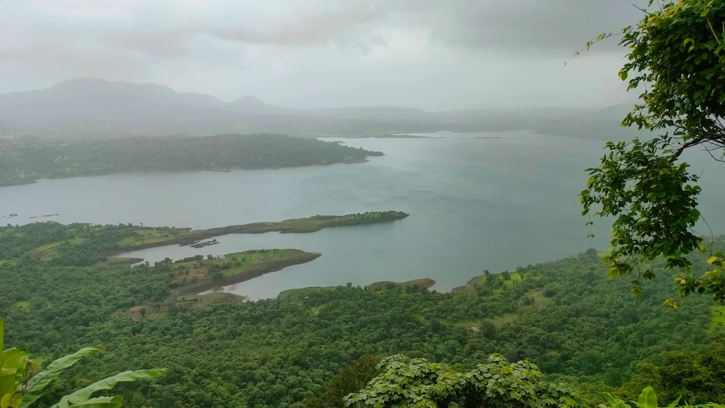 Morbe Dam reservoir and forested islands seen from the slopes of Irshalgad on a cloudy day