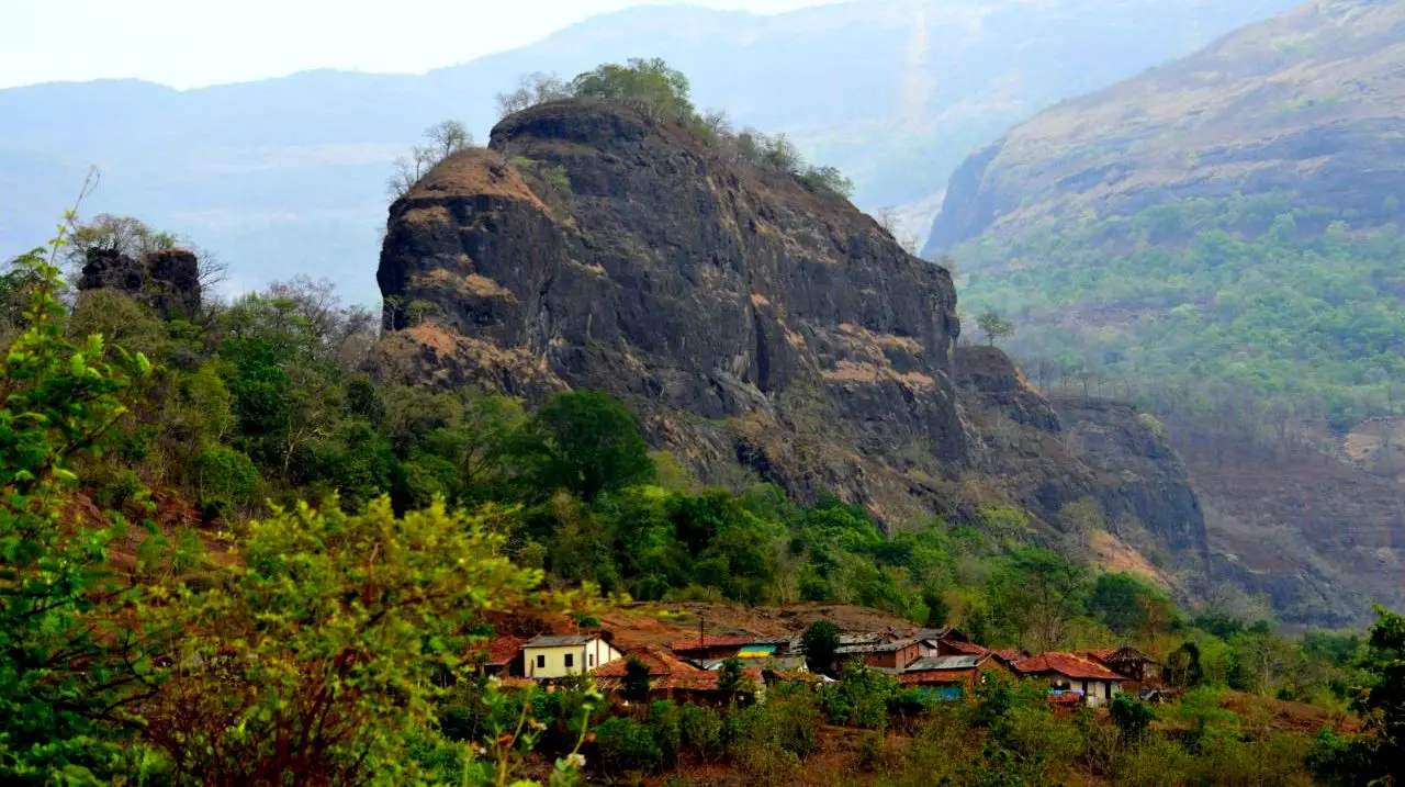 Mrugagad's dark rock pinnacle rising behind the red-roofed houses of the base village