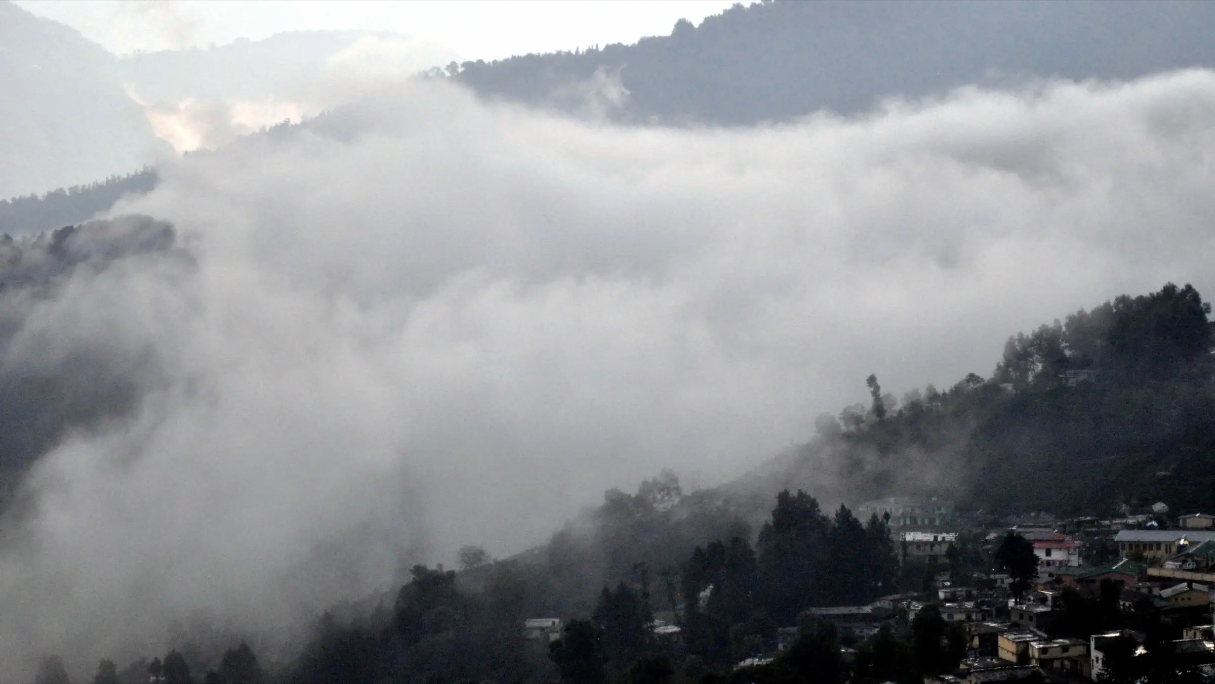 Cloud rolling over the forested hills and houses of Munsiyari, the town where the Puniya Top trek starts and ends