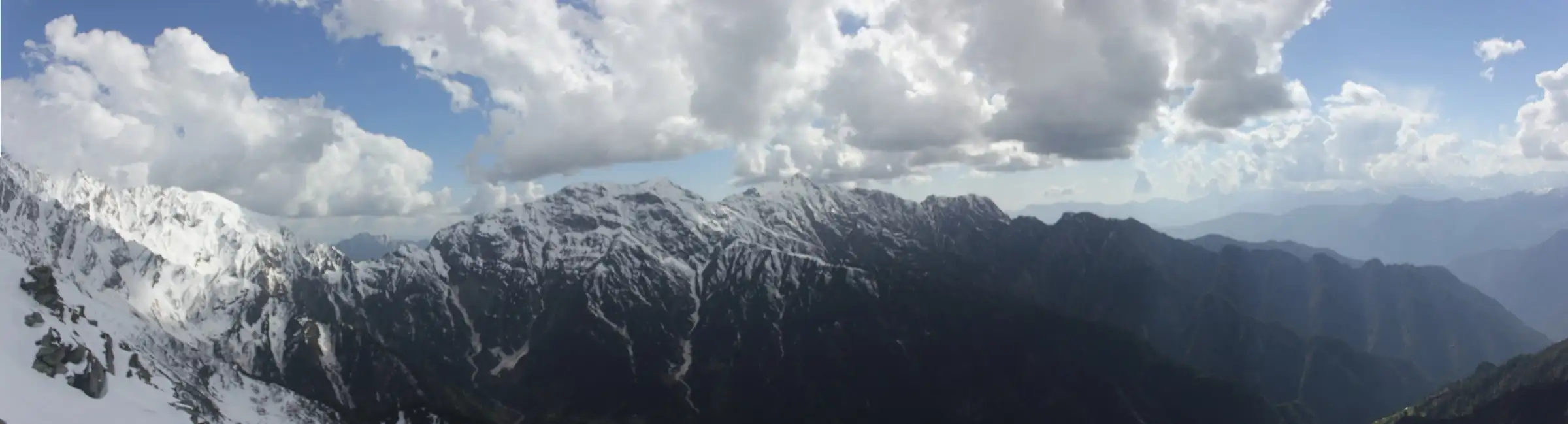 Panorama of snow-streaked ridges under heavy cloud seen from Nagaru, the highest camp on the Sar Pass trek