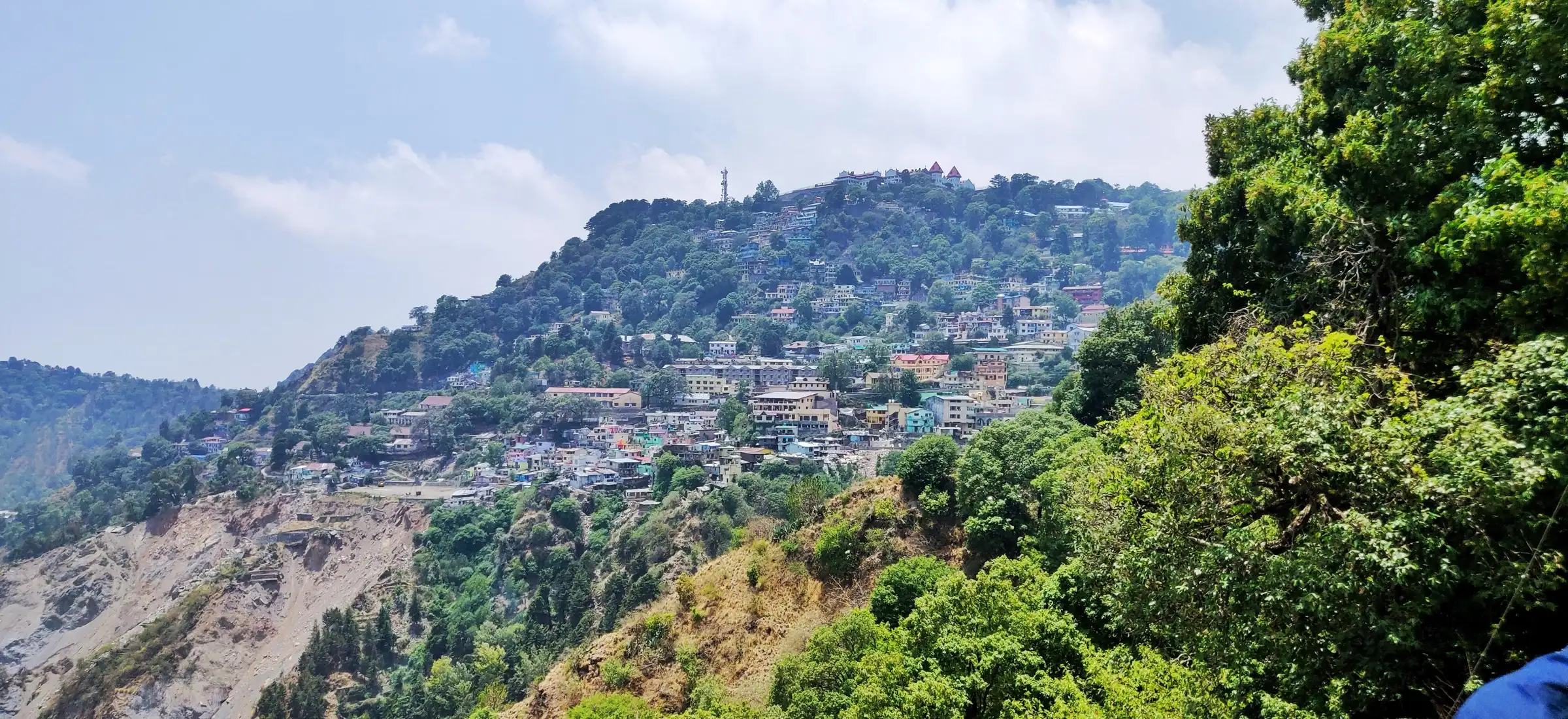 Nainital's houses climbing a wooded ridge, seen from the Bhowali road