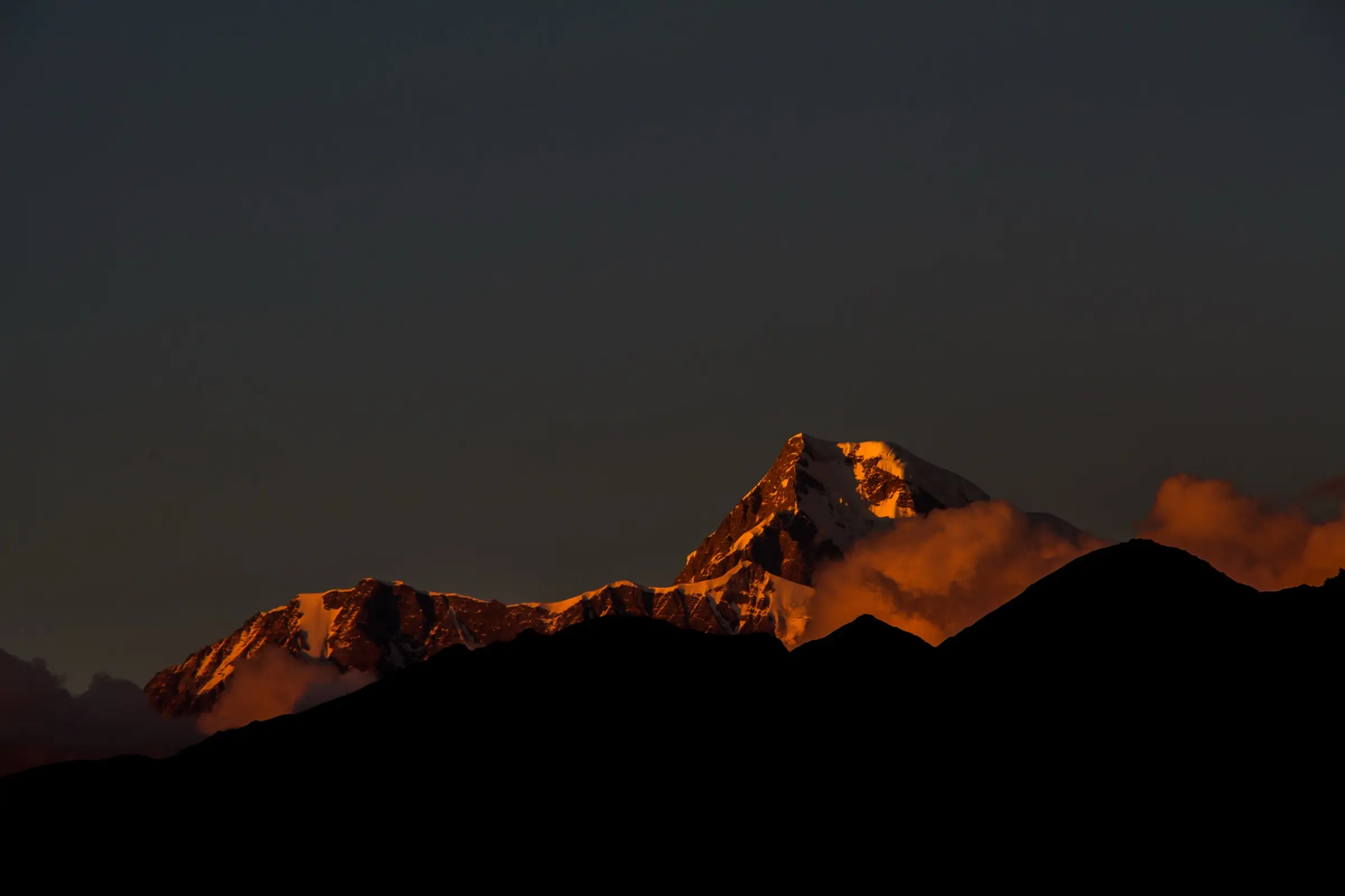 Sunset glow on the snowy summit of Nanda Ghunti above dark ridges, seen from Lohajung