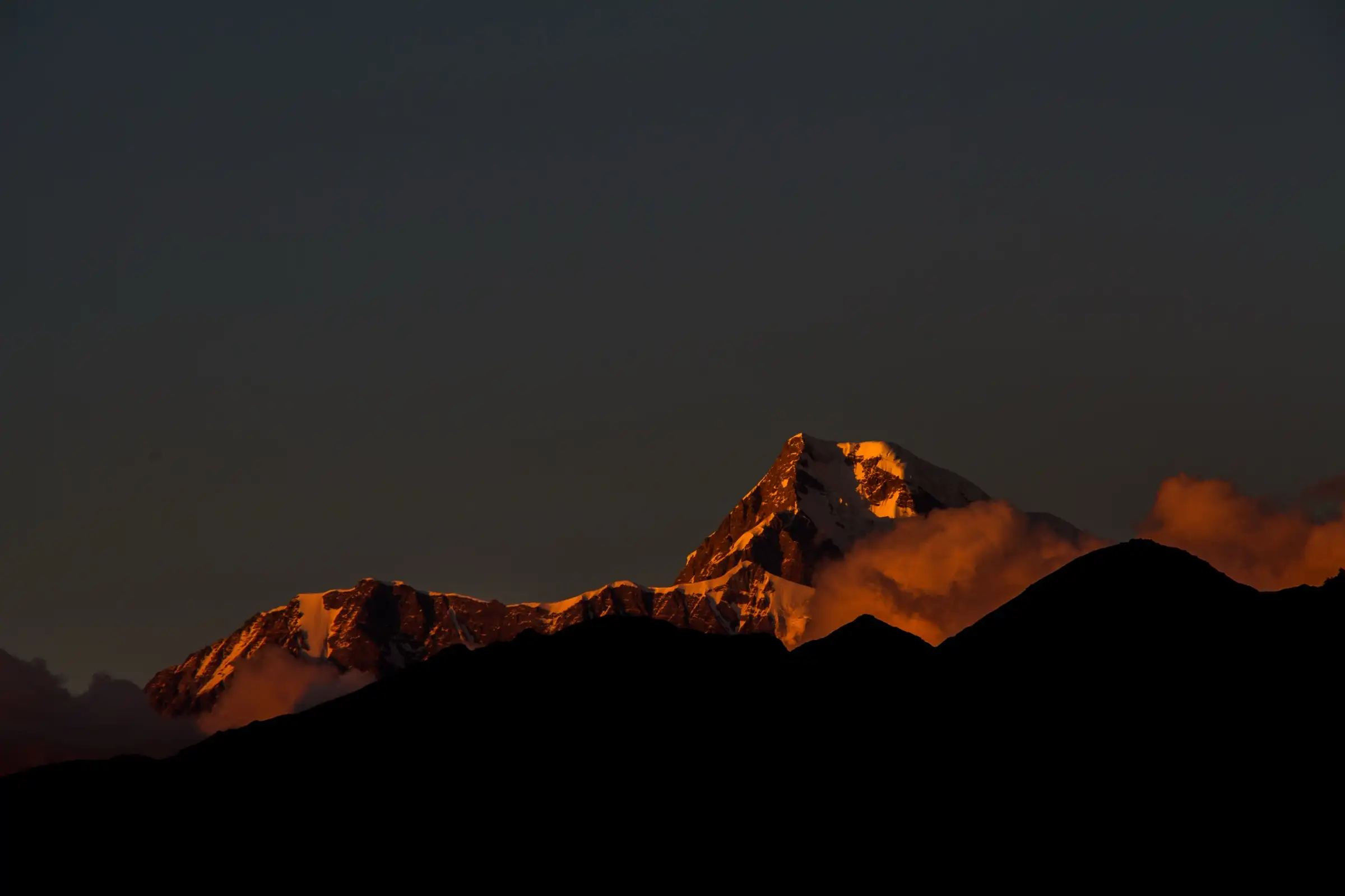 Sunset glow on the snowy summit of Nanda Ghunti above dark ridges, seen from Lohajung
