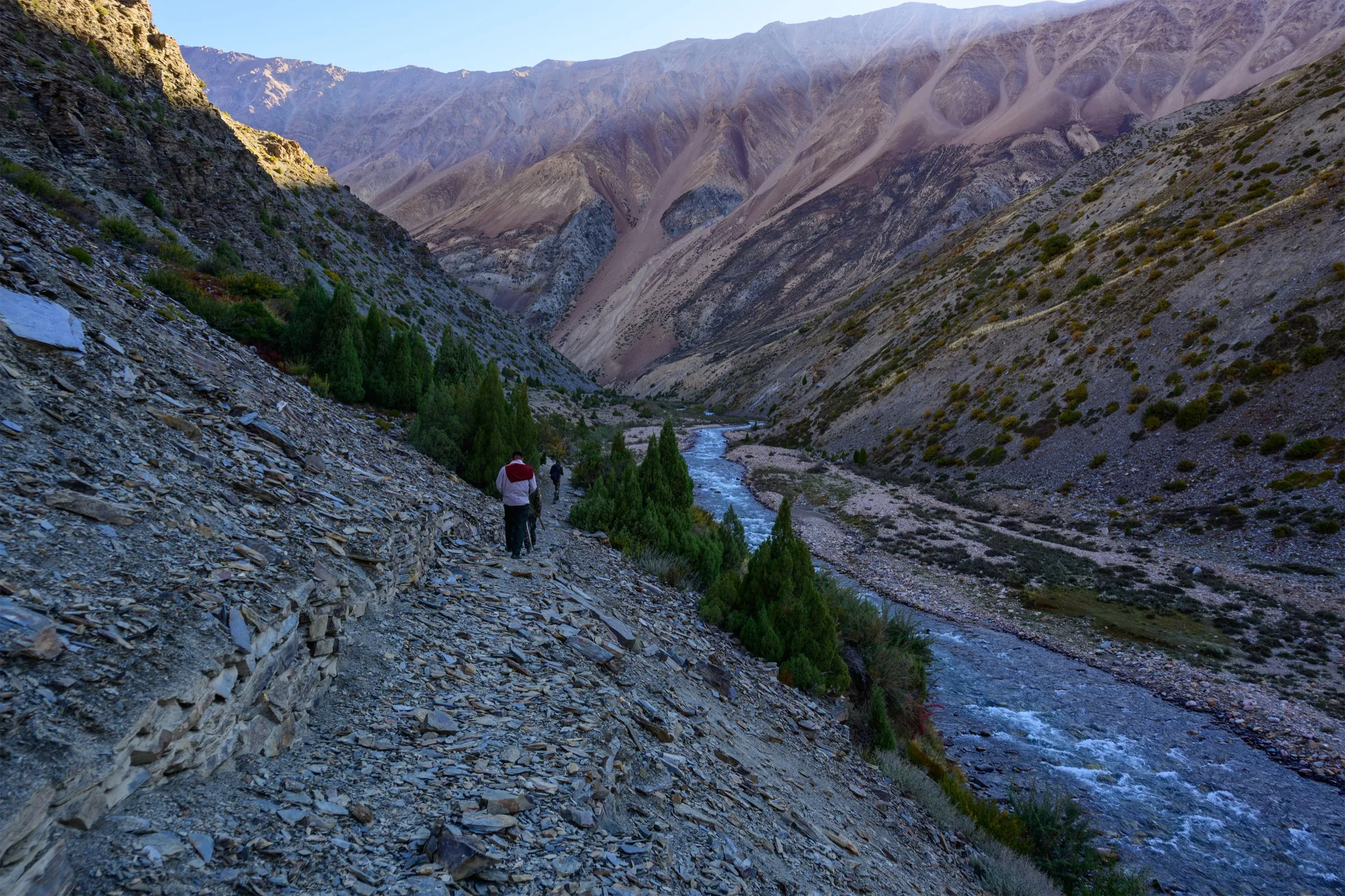 Trekkers on a stony path above the Jadhang Gad river in the bare, steep-walled Nelong Valley