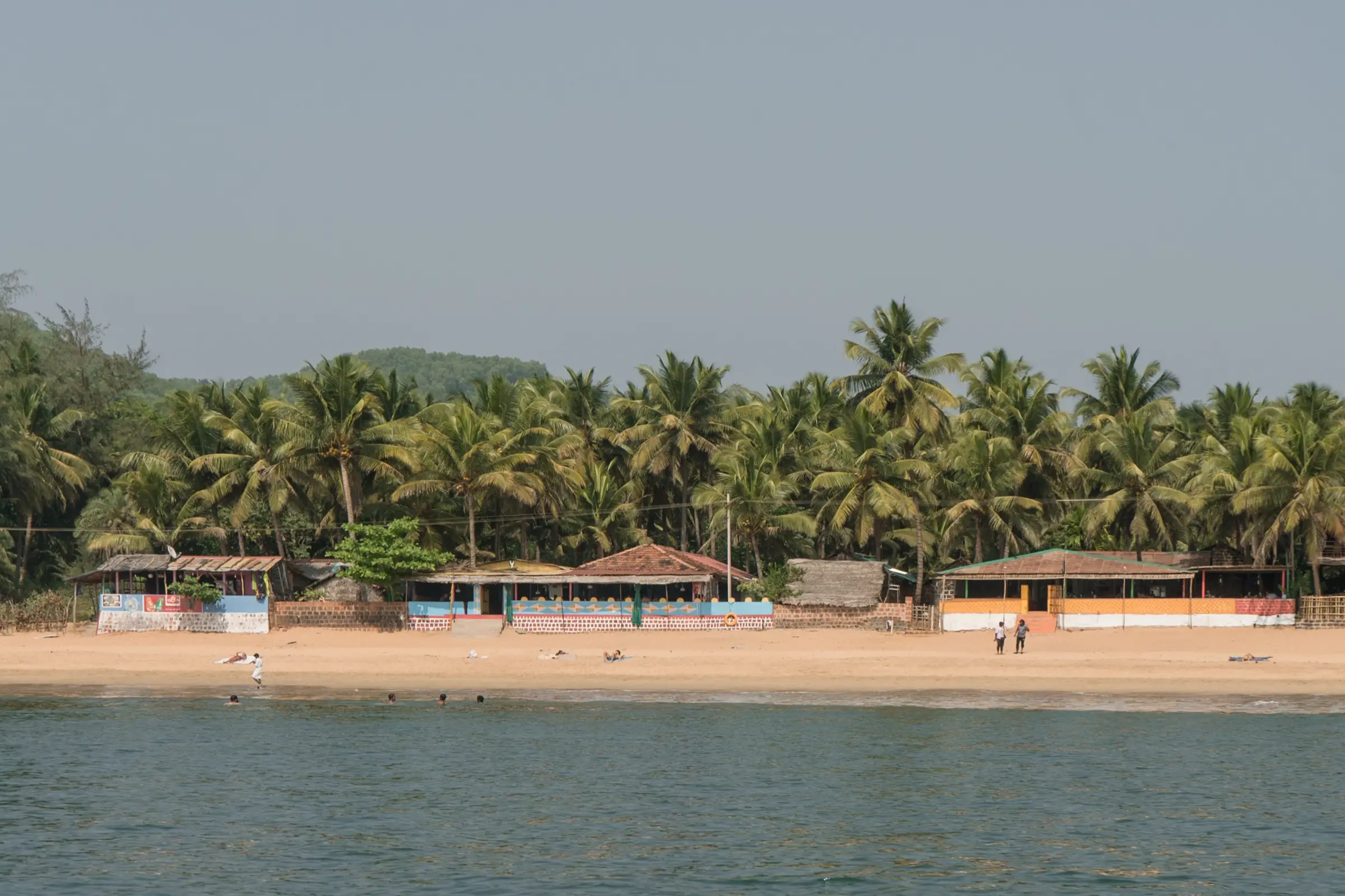 Palm-fringed sand and beach shacks at Om Beach, Gokarna, seen from the sea