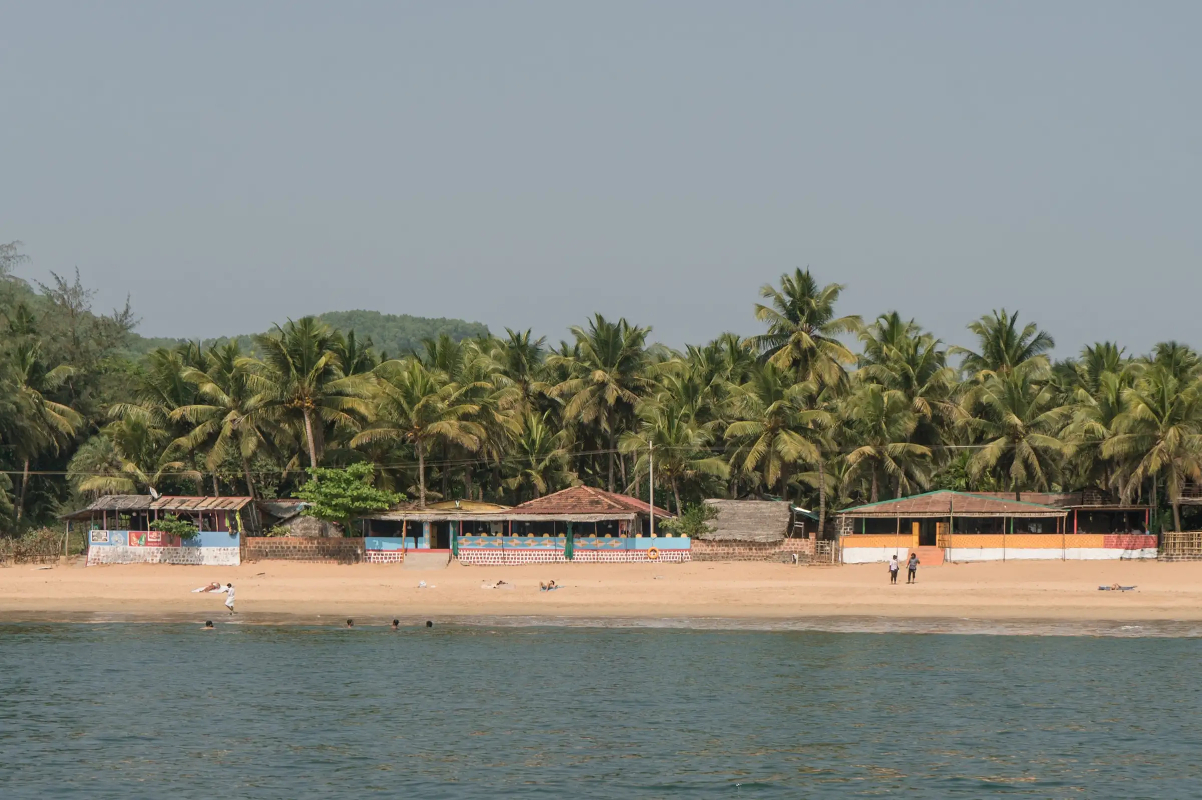 Palm-fringed sand and beach shacks at Om Beach, Gokarna, seen from the sea