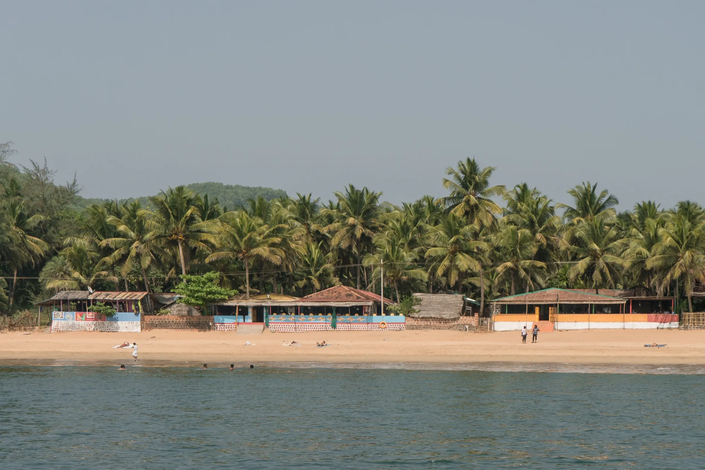 Palm-fringed sand and beach shacks at Om Beach, Gokarna, seen from the sea