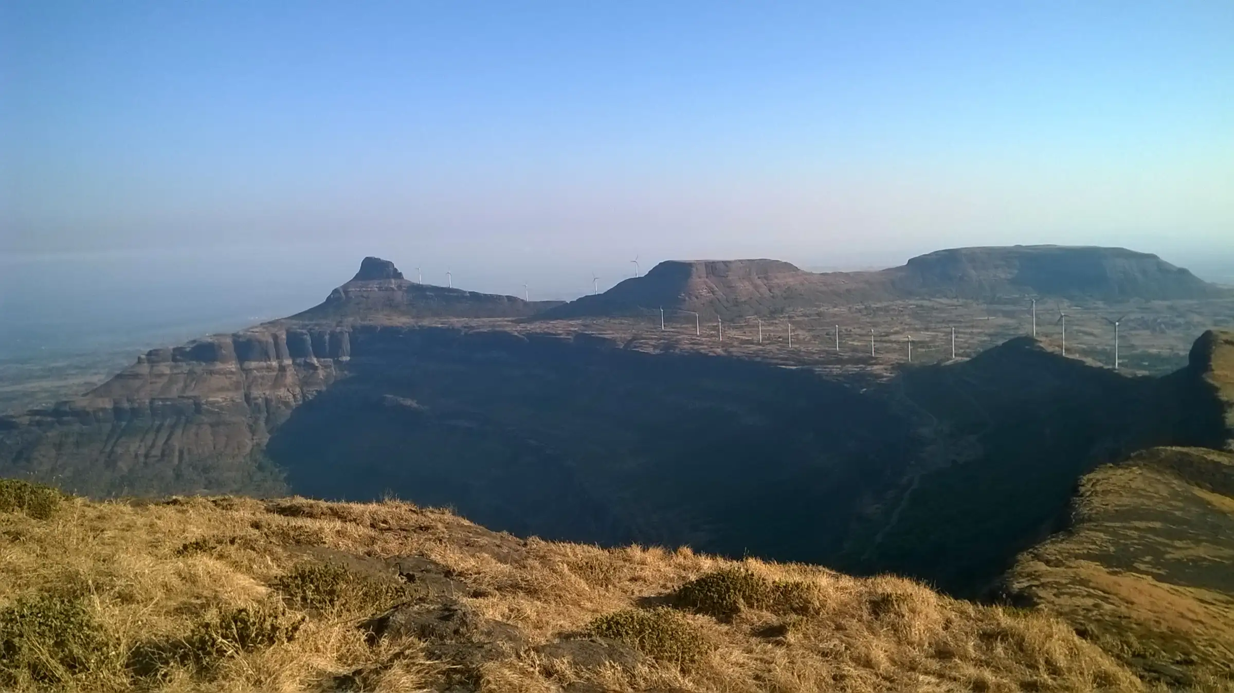 View from the top of Patta Fort over a deep valley towards the flat-topped hills and wind turbines of the Aundha–Patta range