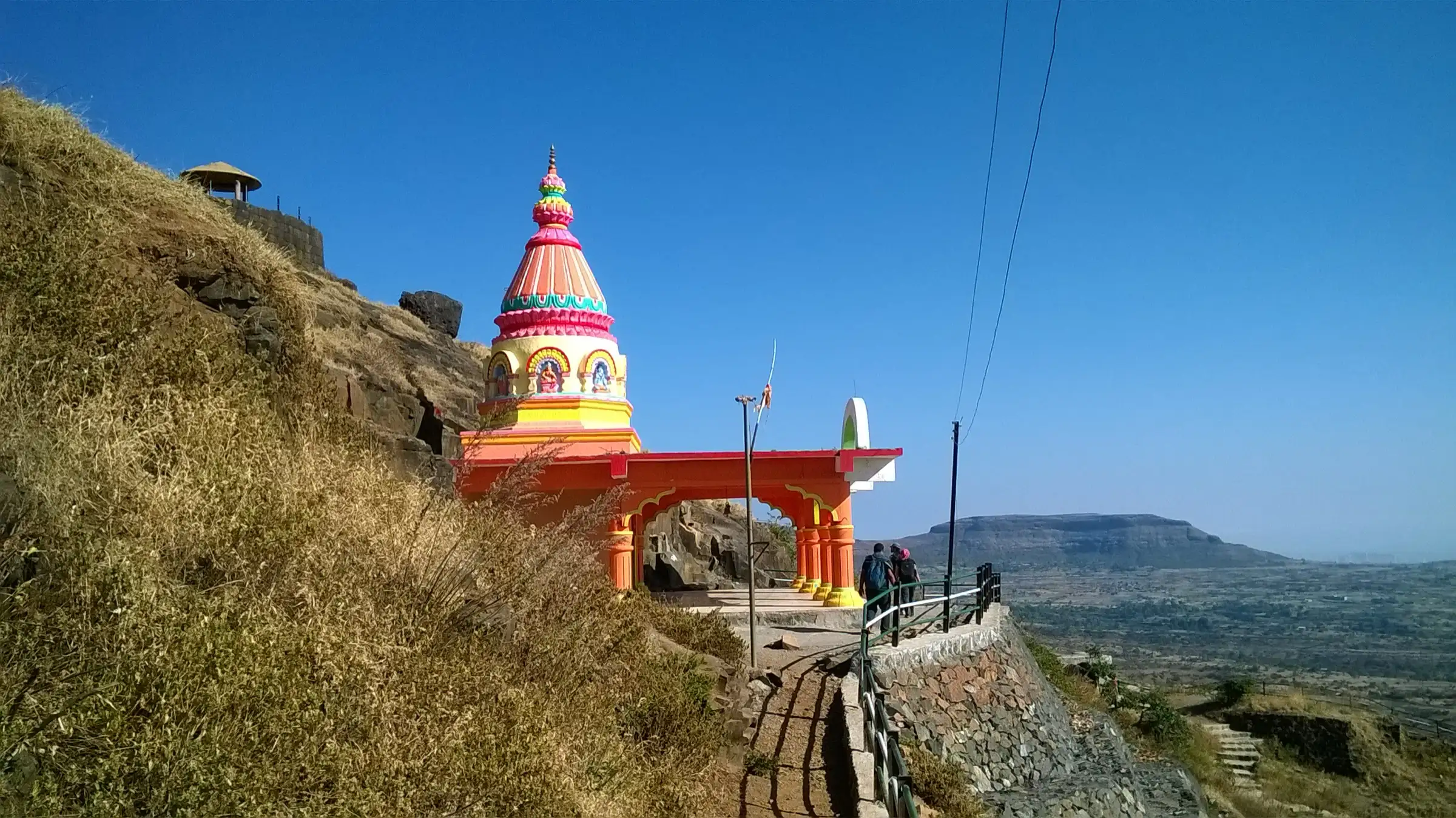 The brightly painted Devi Pattai temple on the stepped path up Patta Fort, with trekkers walking past