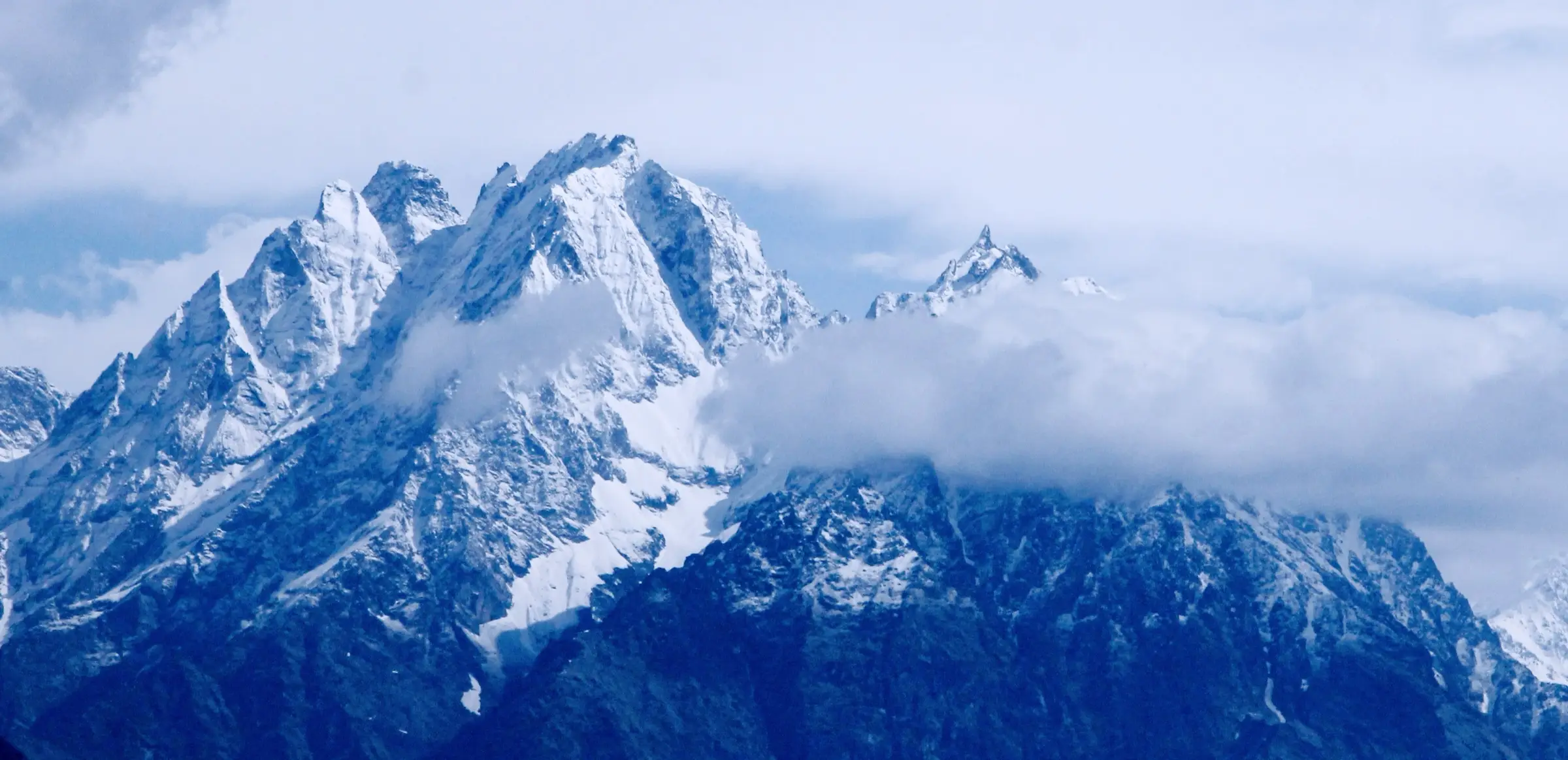 Snow-covered rock peaks rising above cloud, seen from Munsiyari at the start of the Ralam valley trek