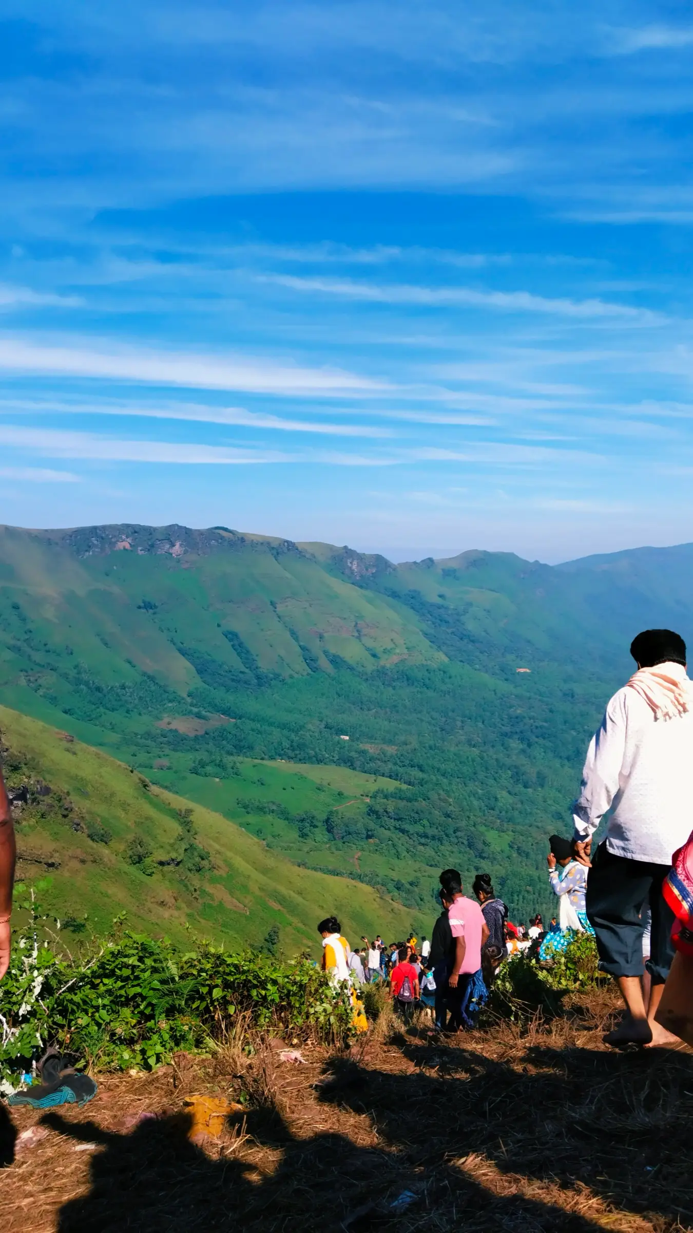 Pilgrims climbing the open hillside to Deviramma Betta during Deepavali, with green valleys below