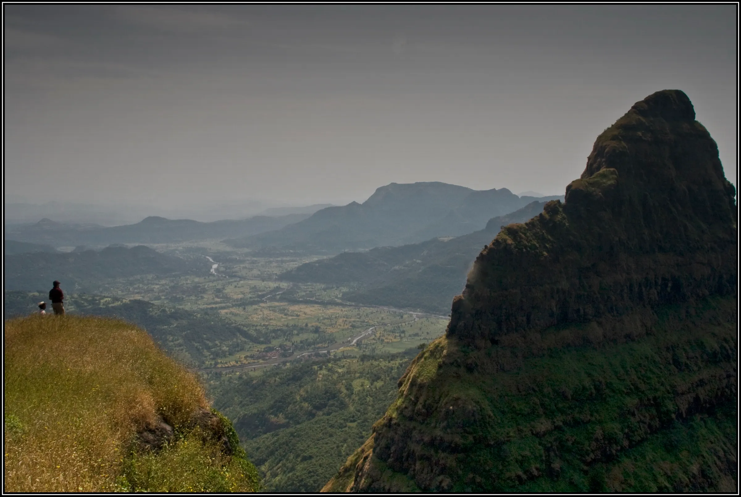 The Lingana pinnacle rising beside the Rayling plateau edge, with two people looking over the Kal river valley