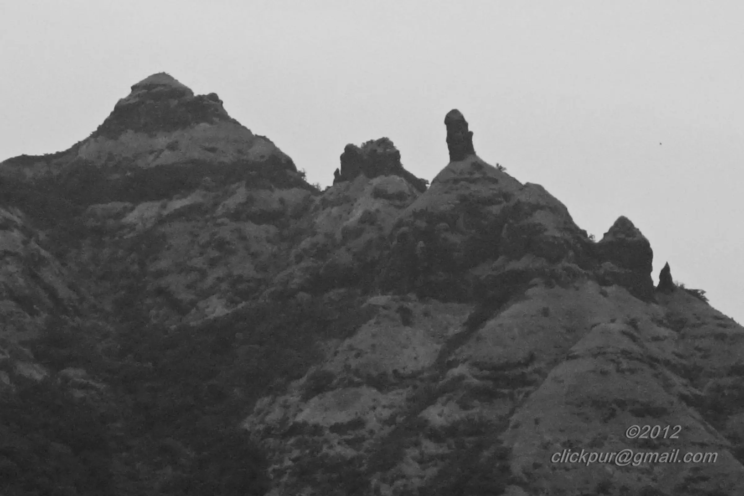 Close view of rocky pinnacles and a slender rock tower on the Chanderi ridge against a grey sky