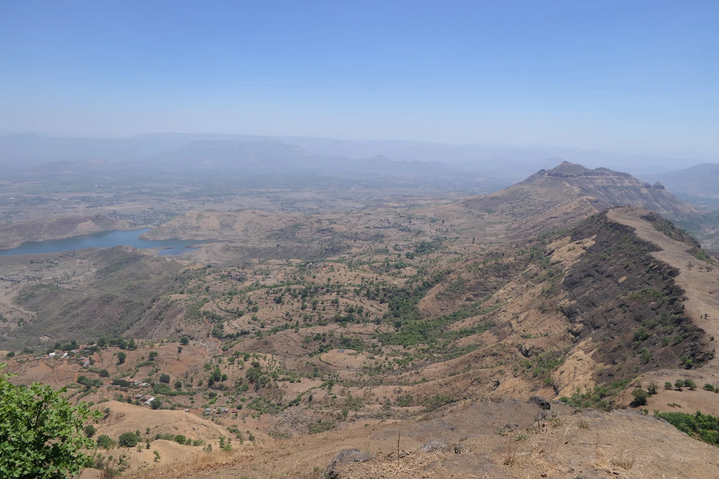 Dry brown Garbett plateau ridge running away from Garbett Point towards a pointed hill, with Dhom lake and farmland in the valley on the left