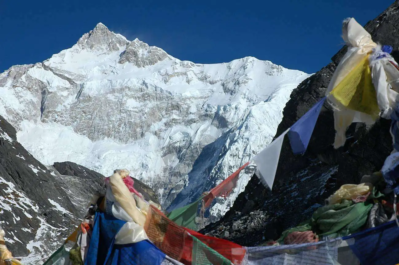 Colourful prayer flags in the foreground with the snow-covered south-east face of Kanchenjunga behind