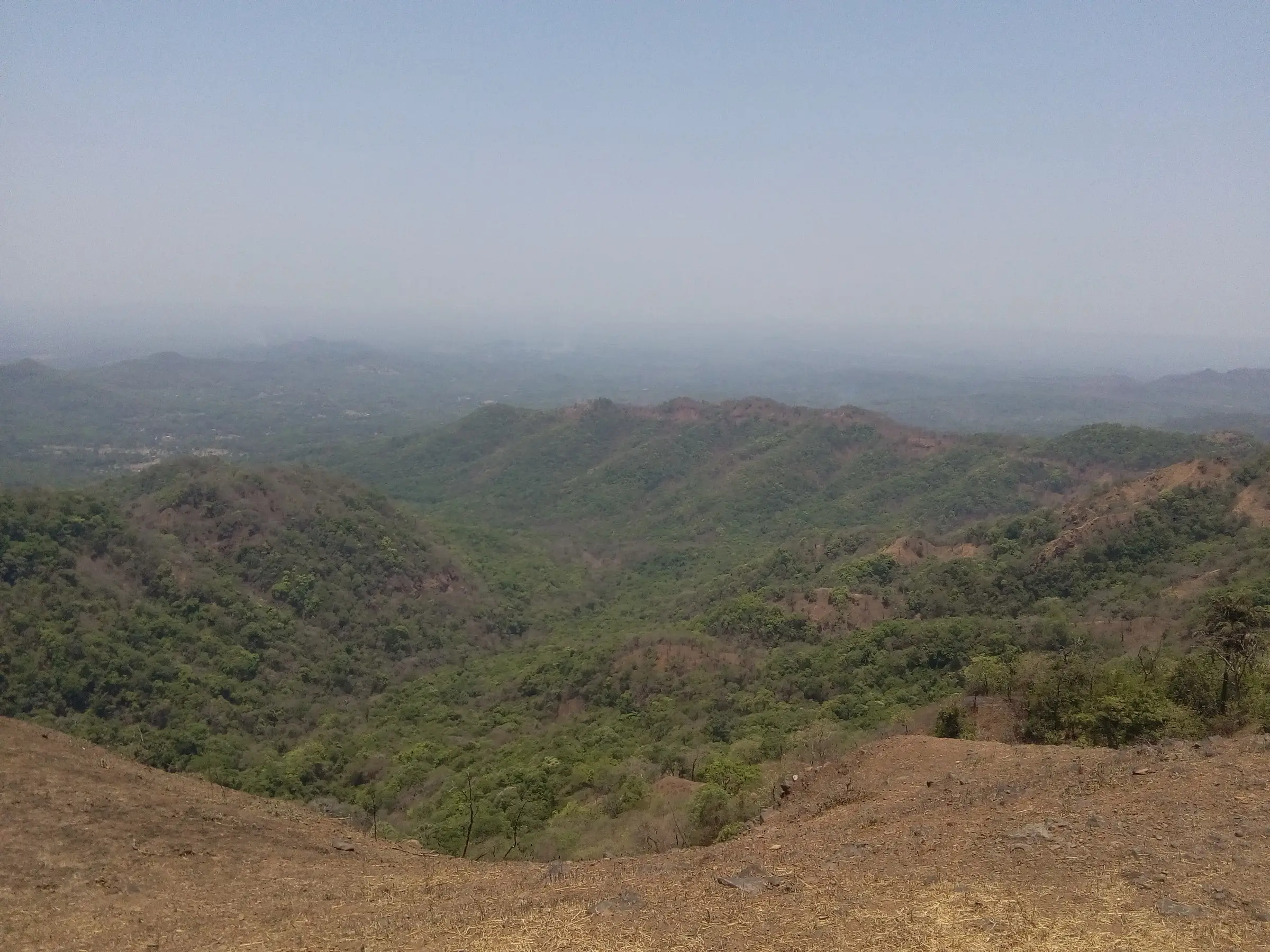 View from Rangana Fort over forested Sahyadri ridges and valleys fading into haze towards the Konkan
