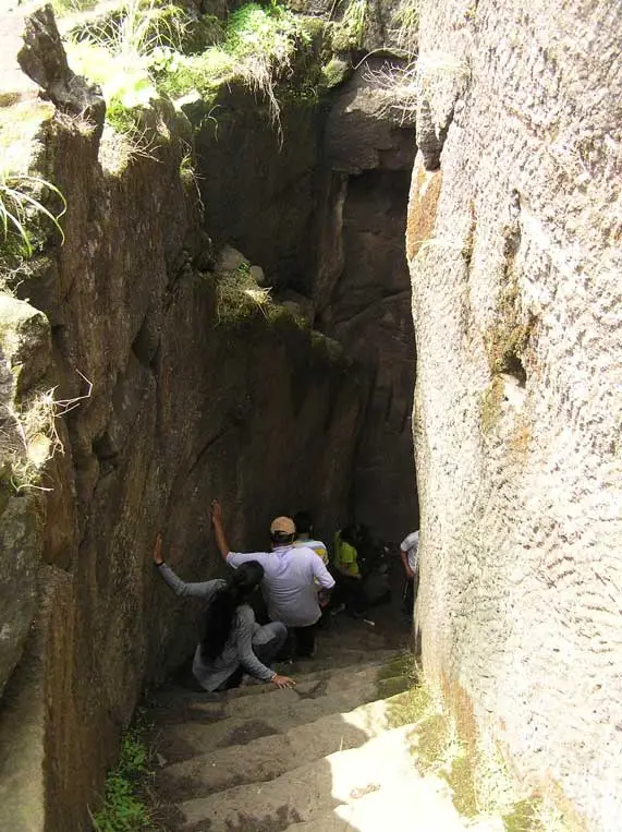 Trekkers descending the narrow rock-cut staircase that leads to the top of Kothaligad