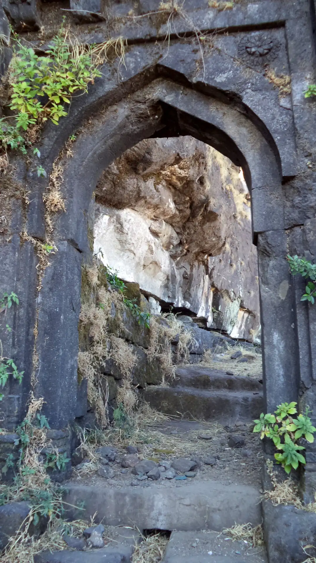 Stone archway of a fort gate on Salher with worn rock-cut steps climbing through it