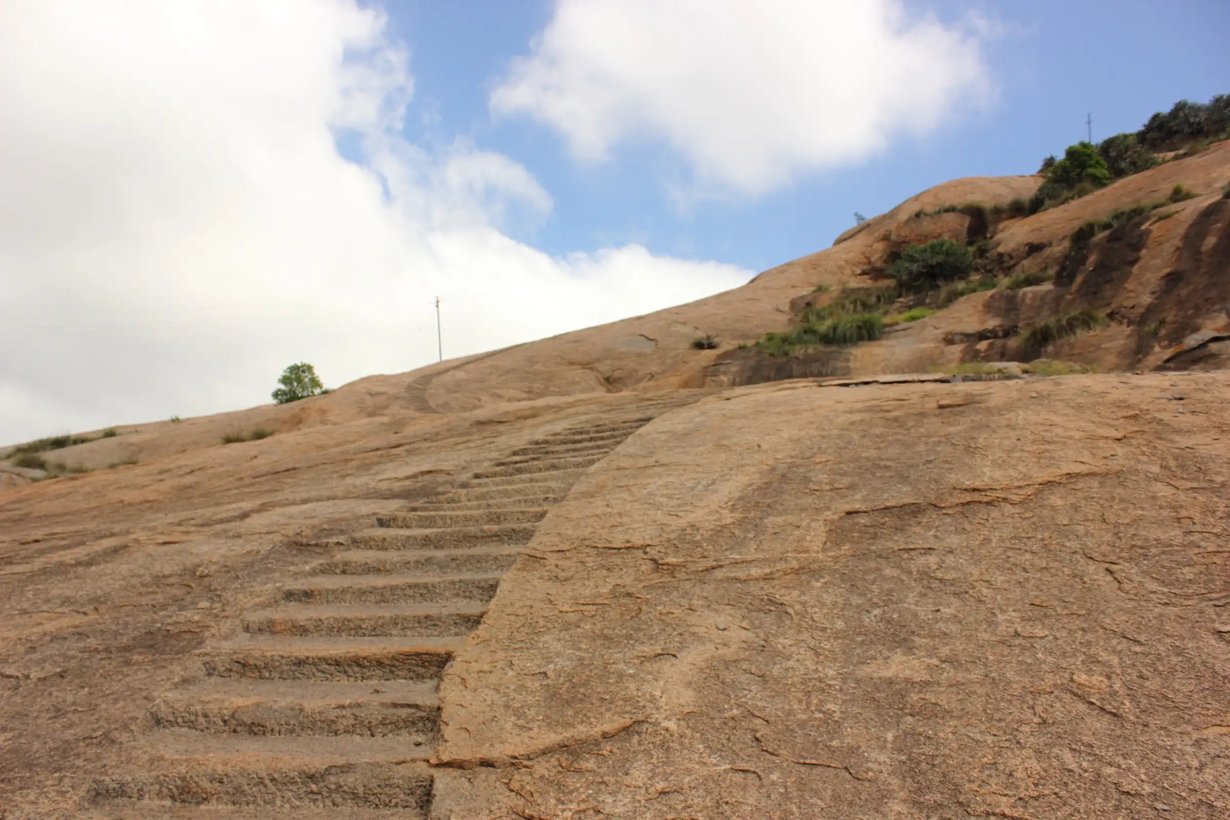 Steps cut into a bare granite slope on the climb up Hutridurga under a cloudy sky