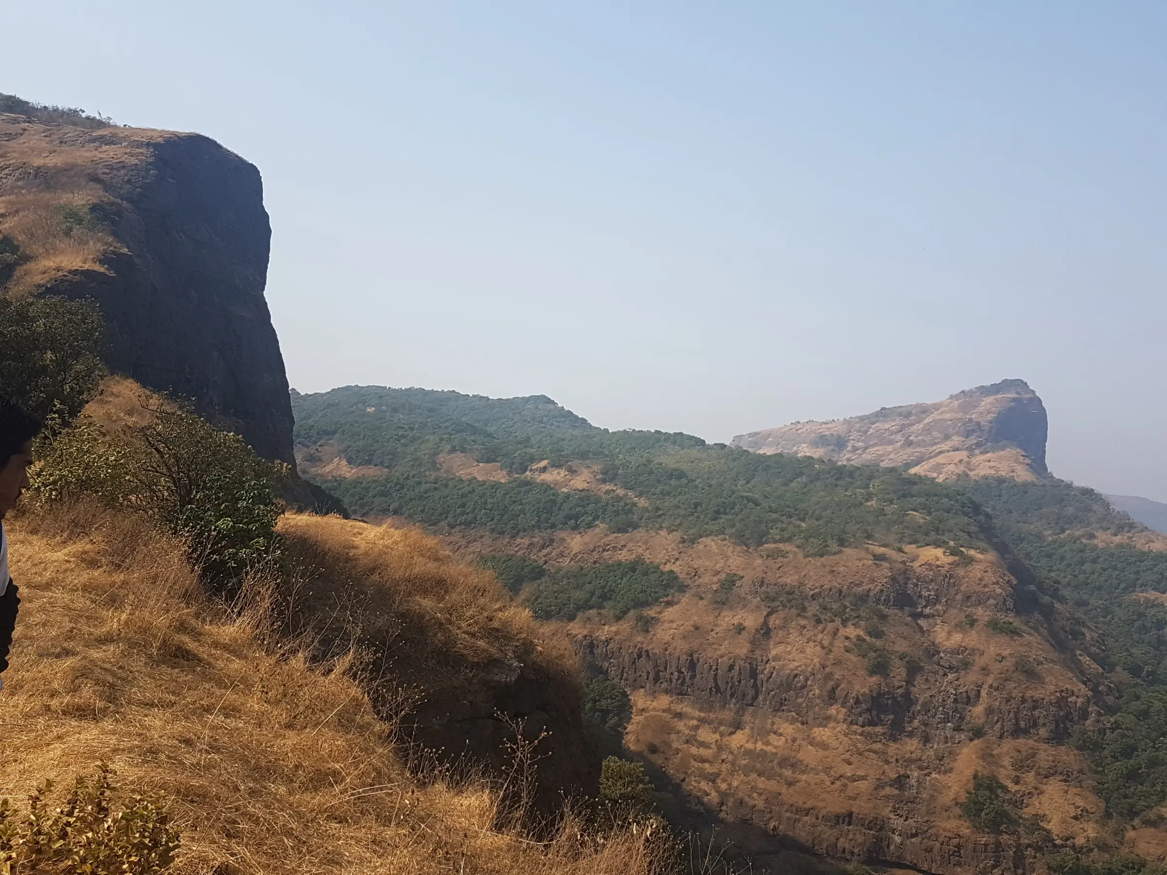 Dry grass slopes and forested cliffs of the Sahyadri scarp on the approach to Dhak Bahiri