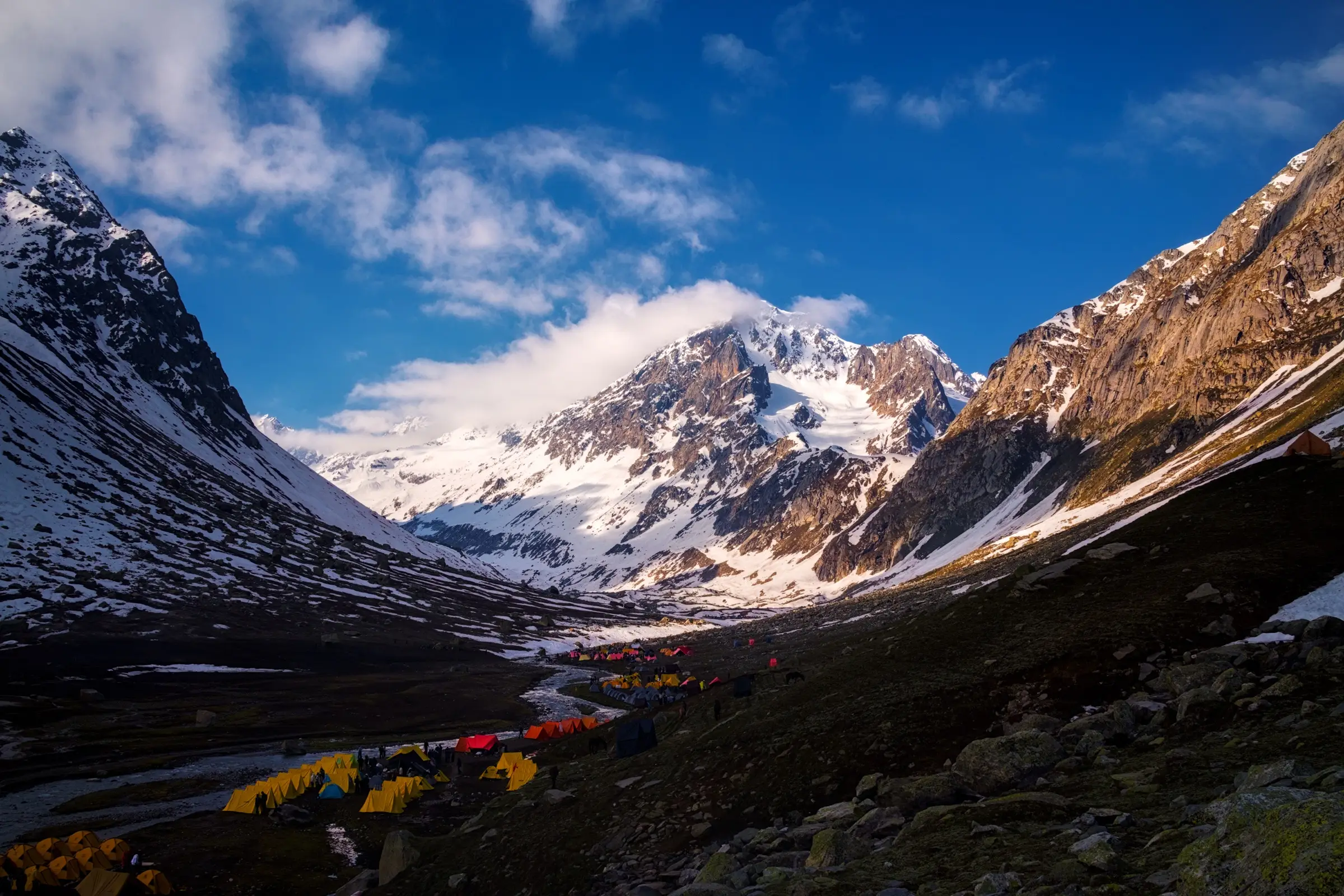 Tents at Shea Goru campsite below snow-covered Mount Indrasan on the Hampta Pass trek
