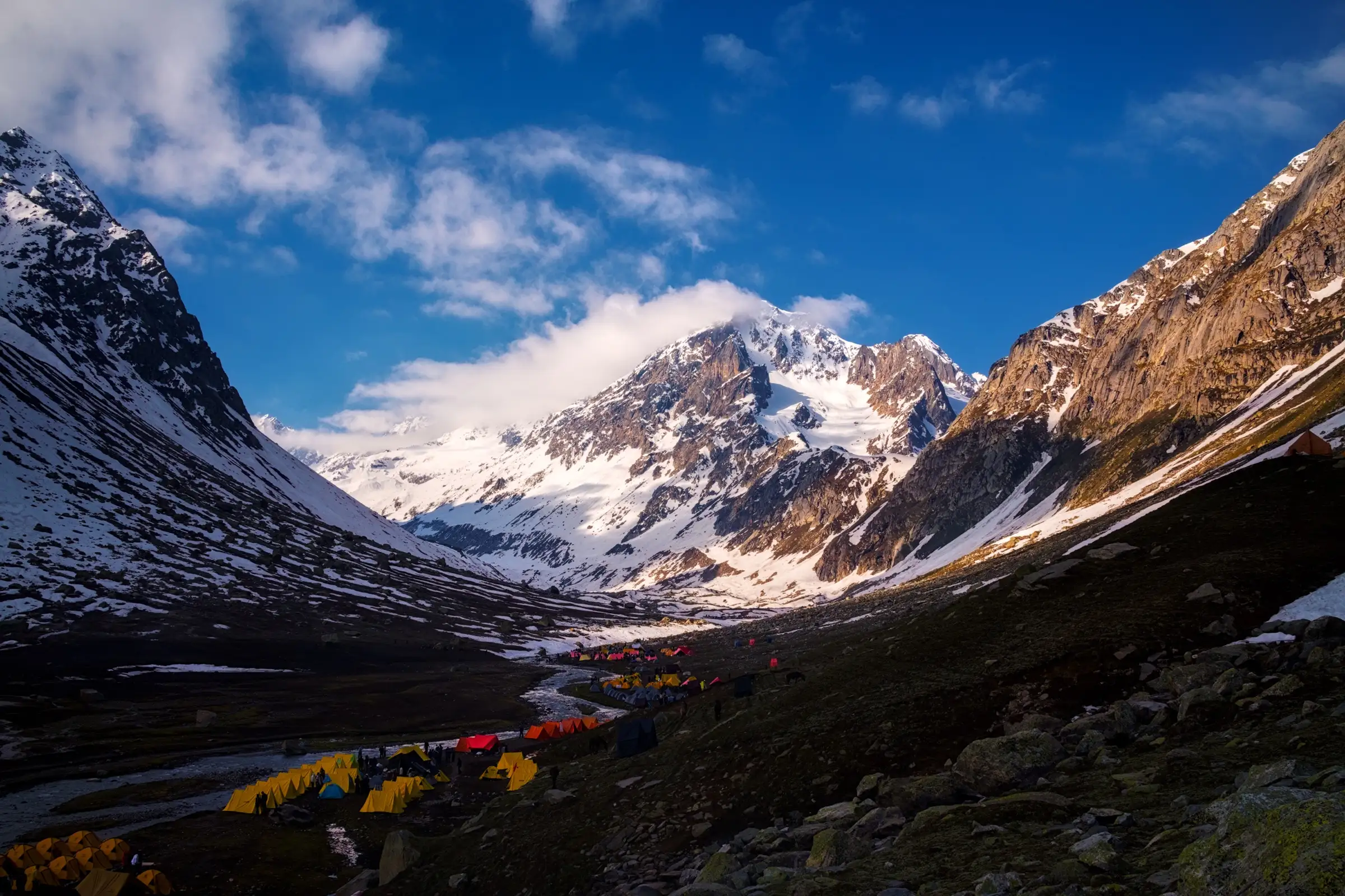 Tents at Shea Goru campsite below snow-covered Mount Indrasan on the Hampta Pass trek