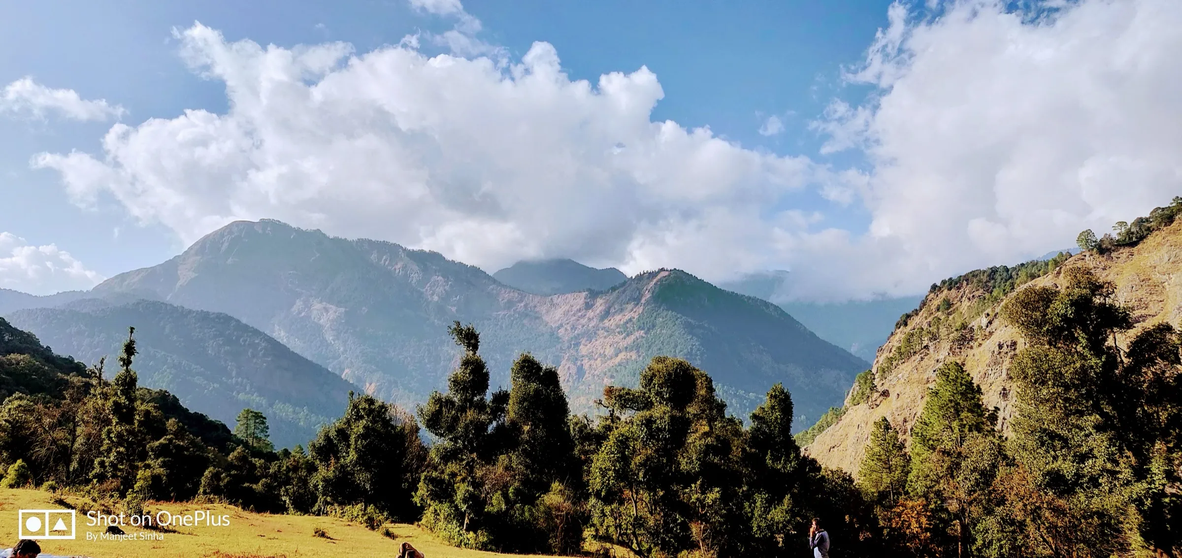 Forested ridges of the Assi Ganga valley under white clouds, seen from the Shiladuni campsite meadow