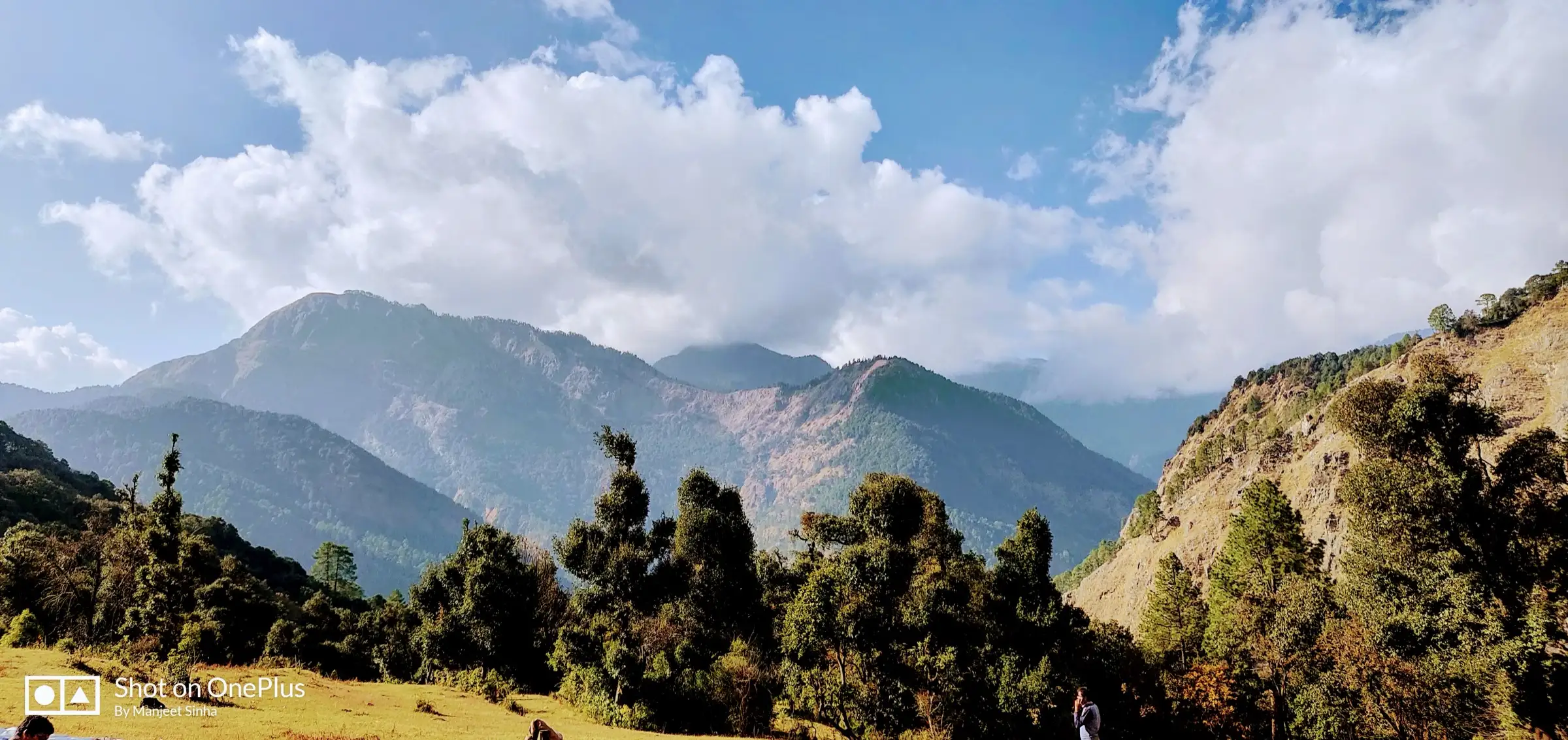 Forested ridges of the Assi Ganga valley under white clouds, seen from the Shiladuni campsite meadow