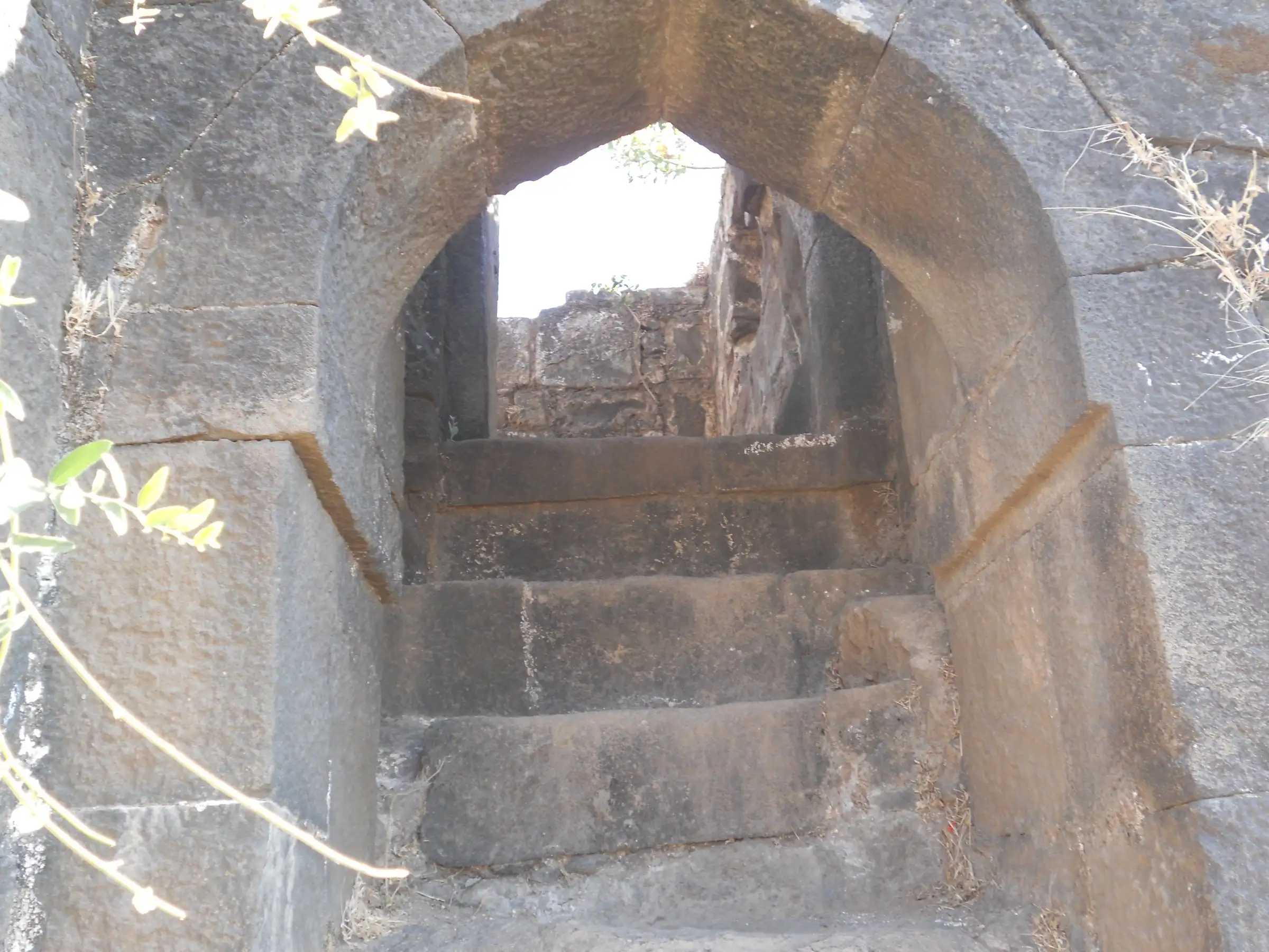 Stone steps rising through an arched gateway built of dark stone blocks on Ramshej Fort