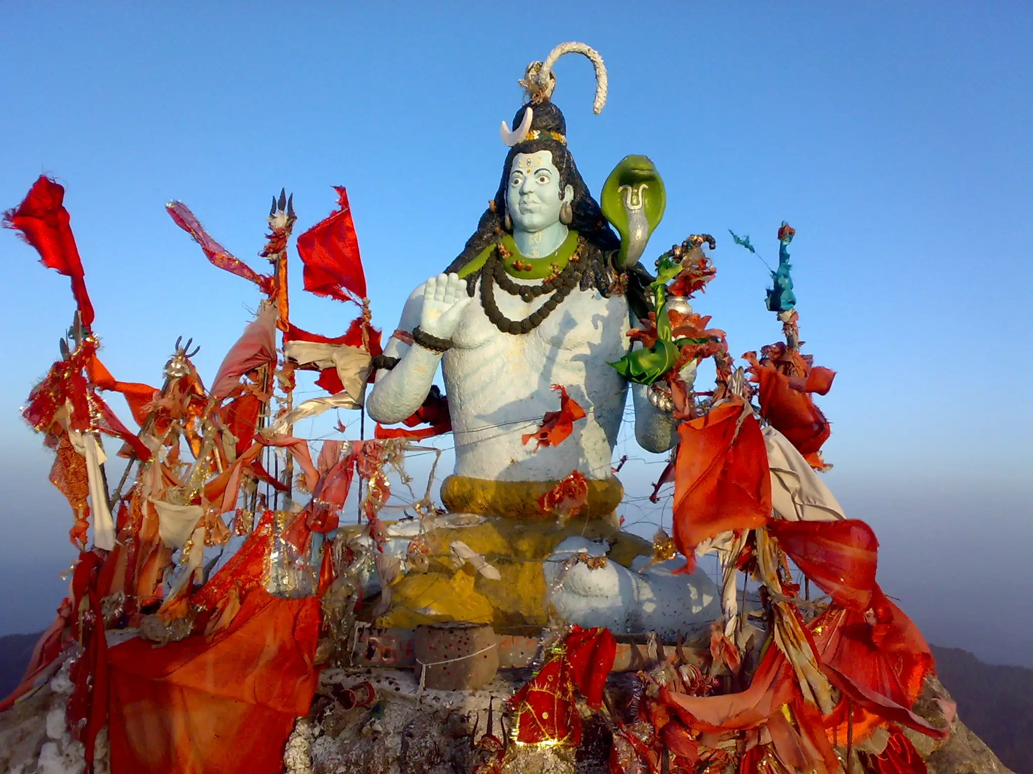 White murti of Bhagwan Shiva on the Churdhar summit, surrounded by red and saffron flags