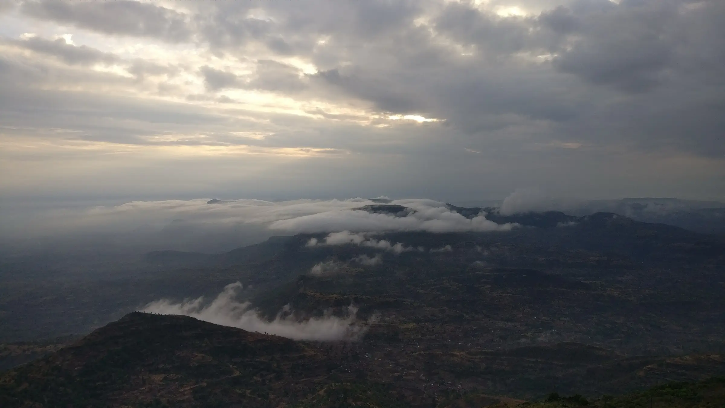 Clouds rolling over Sahyadri ridges at sunrise, seen from the Kalsubai summit