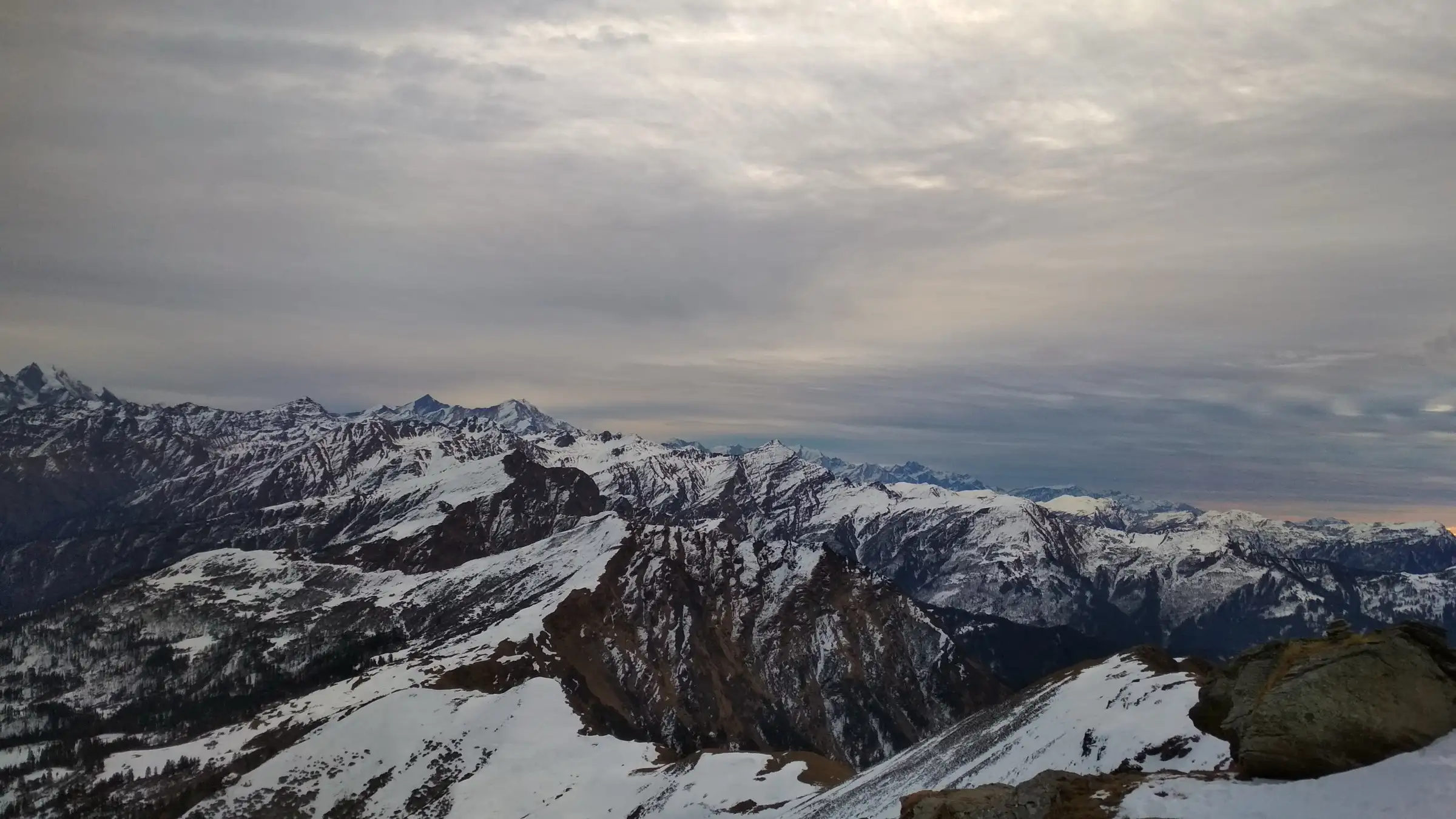 Snowy Himalayan ranges under grey cloud seen from the Kedarkantha summit