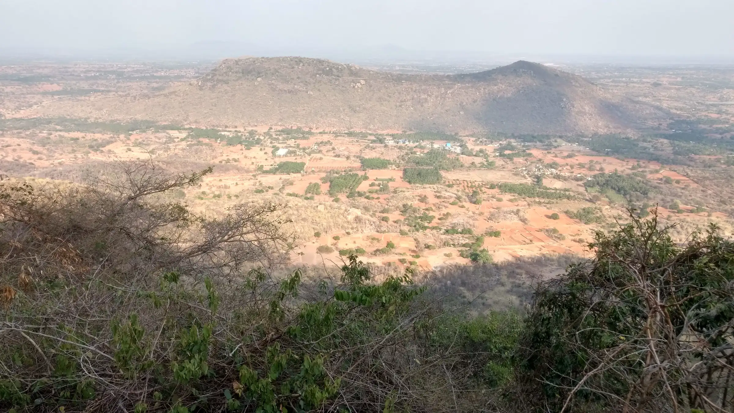 Dry-season view from Devarayanadurga over farmland and a rocky hill, in the countryside around Minchukallu Betta (not the trek itself)