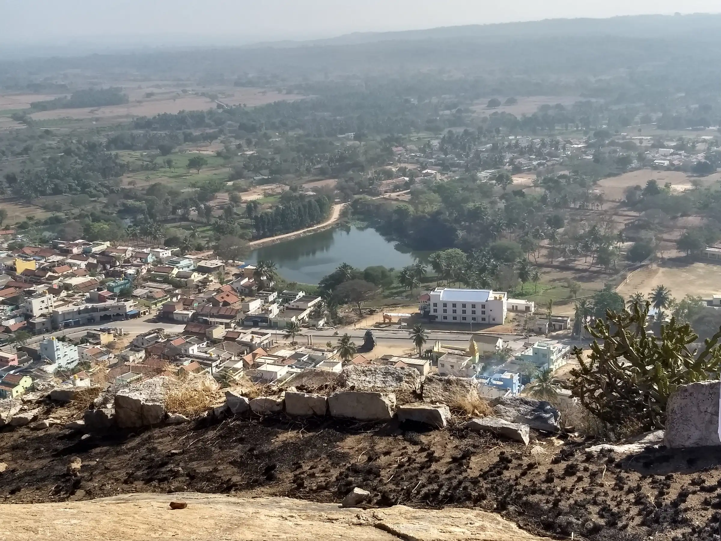 View from the top of Huliyurdurga hill over the stone fort wall to the town, its lake and farmland below