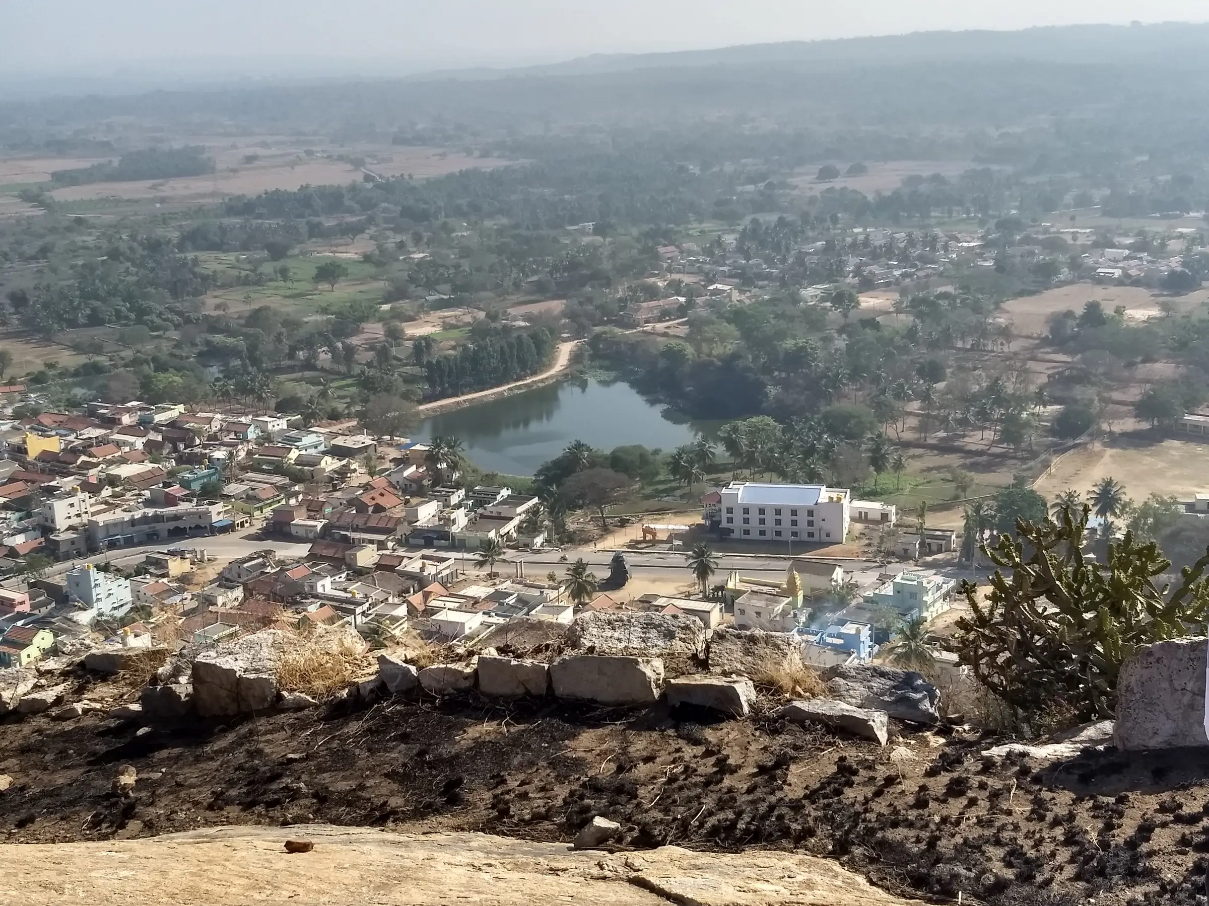 View from the top of Huliyurdurga hill over the stone fort wall to the town, its lake and farmland below