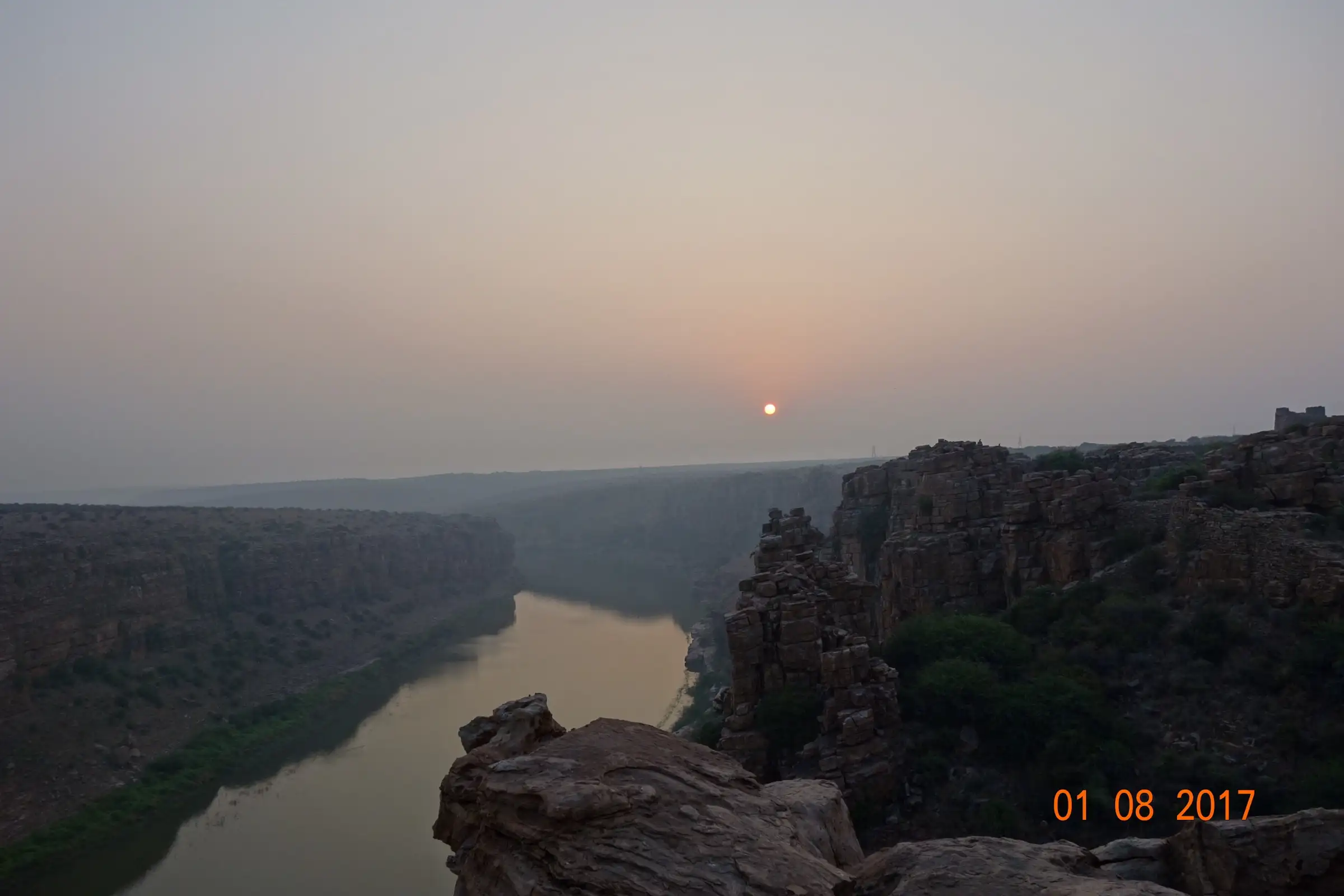 Hazy sunrise over the Gandikota gorge, with the Penna river below dark rocky cliffs