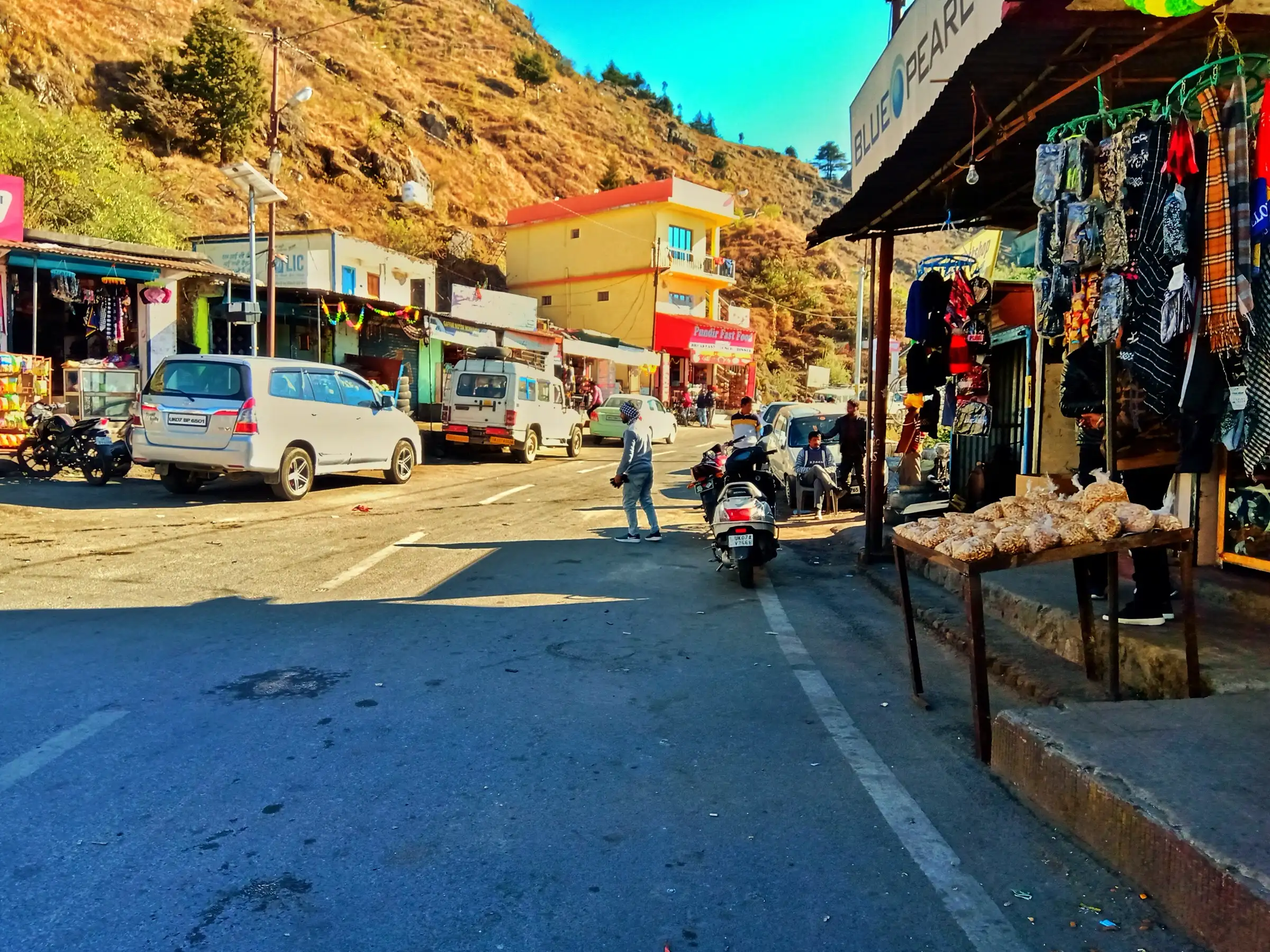 Shops and parked cars on the Dhanaulti road at Suwakholi market, the start point for the Top Tibba hike