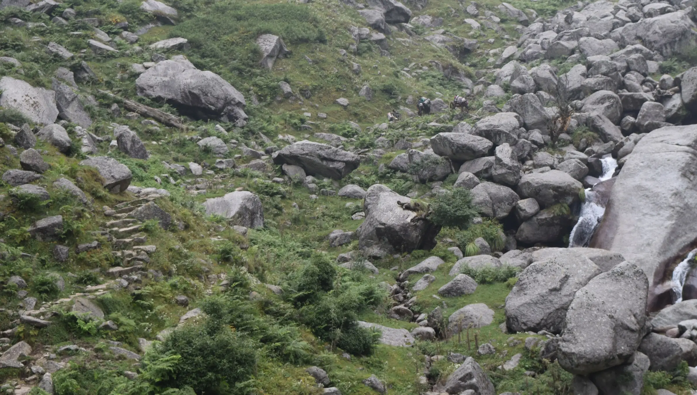 Stone-stepped Kareri trail climbing through boulders and grass beside the Nyund stream