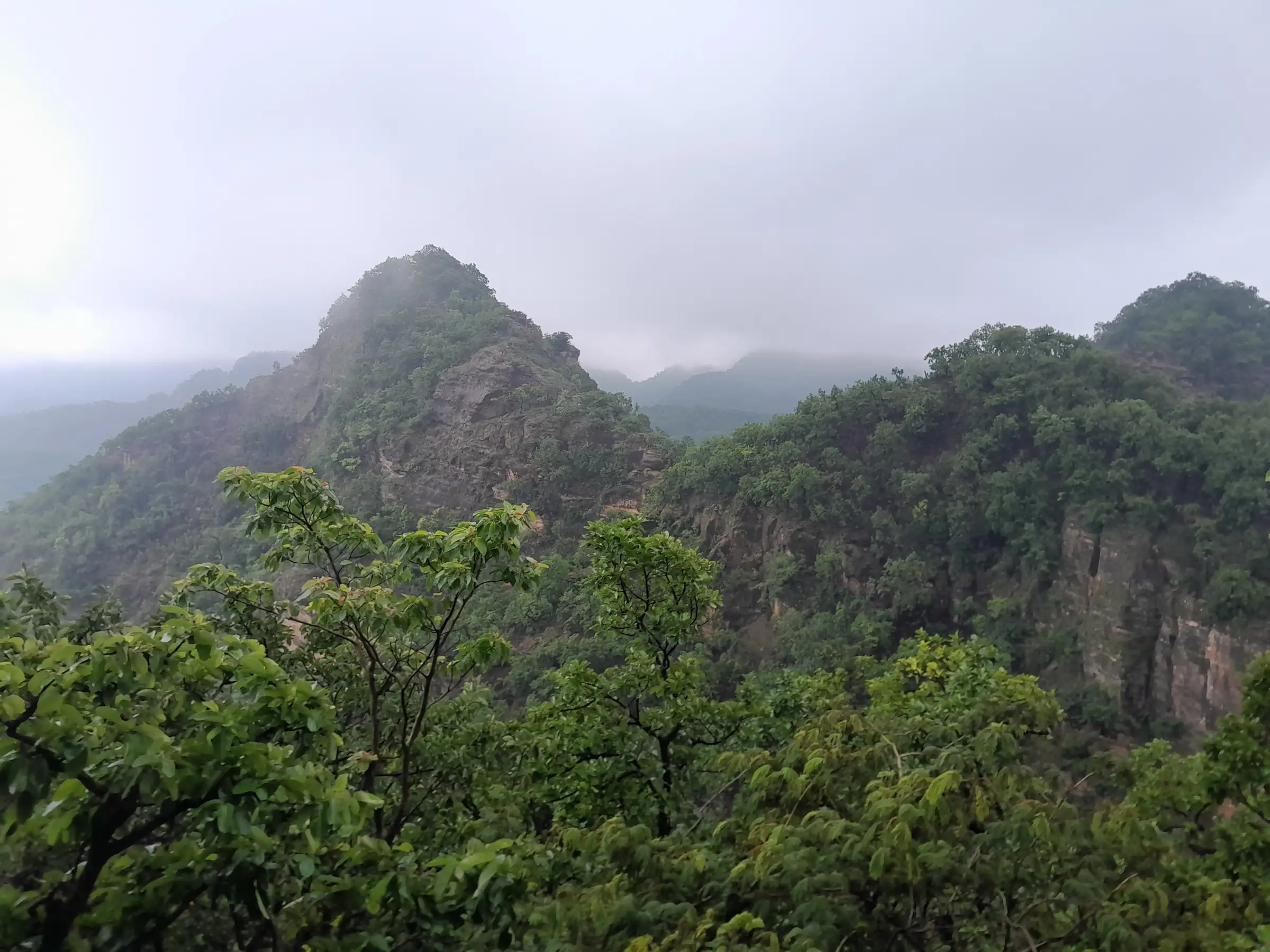 Green monsoon forest and misty rocky peaks seen from the Chauragarh trek route