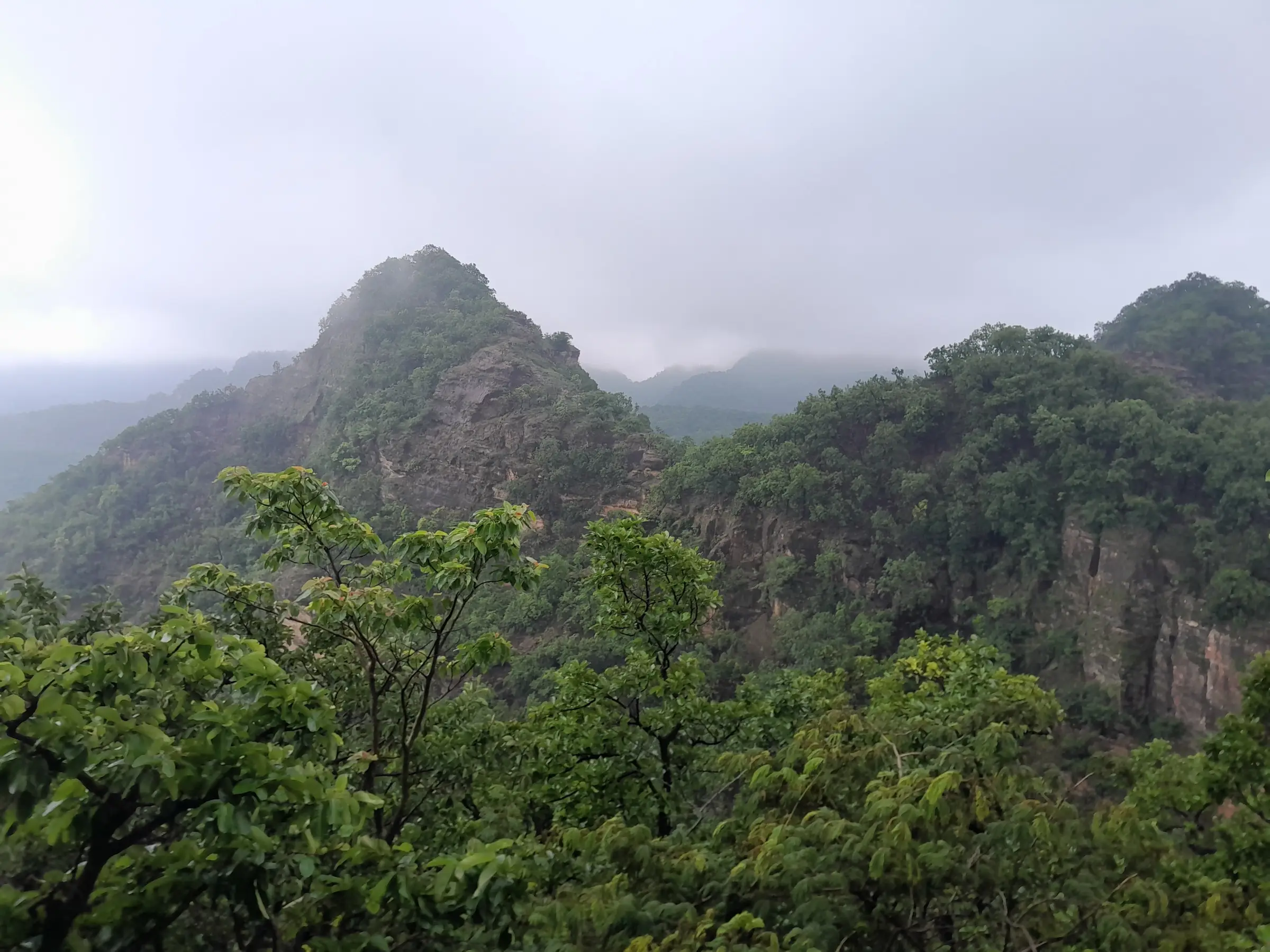 Green monsoon forest and misty rocky peaks seen from the Chauragarh trek route