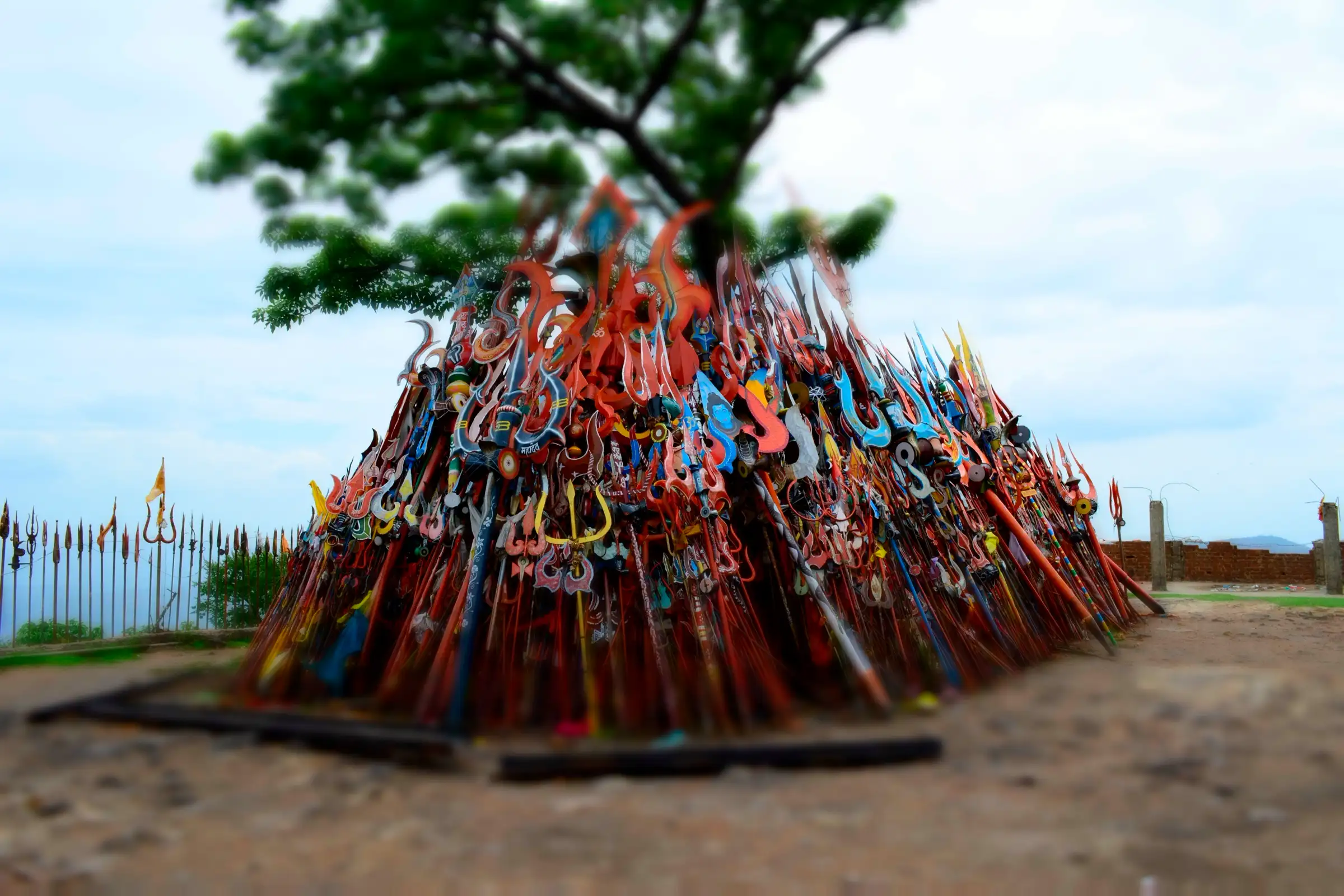 A tall heap of colourful tridents offered by pilgrims in the Chauragarh temple courtyard