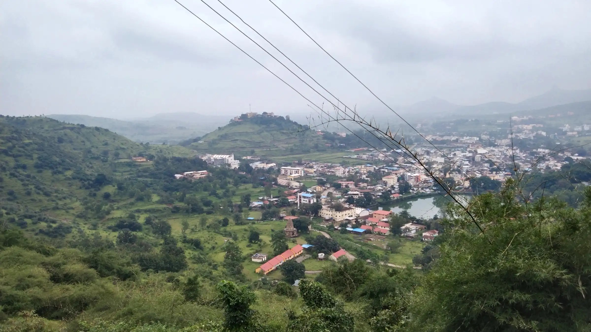 Trimbak town, a temple tank and green hills seen from the Brahmagiri slopes on a cloudy day
