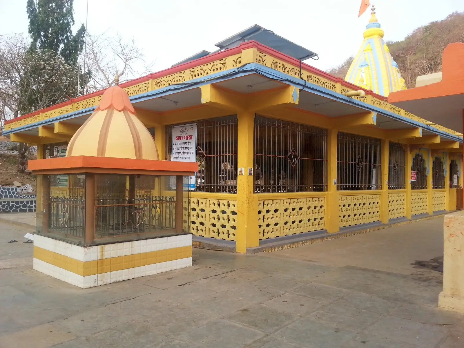 The yellow-pillared Tungareshwar Mahadev temple with its saffron flag and shikhara, Vasai