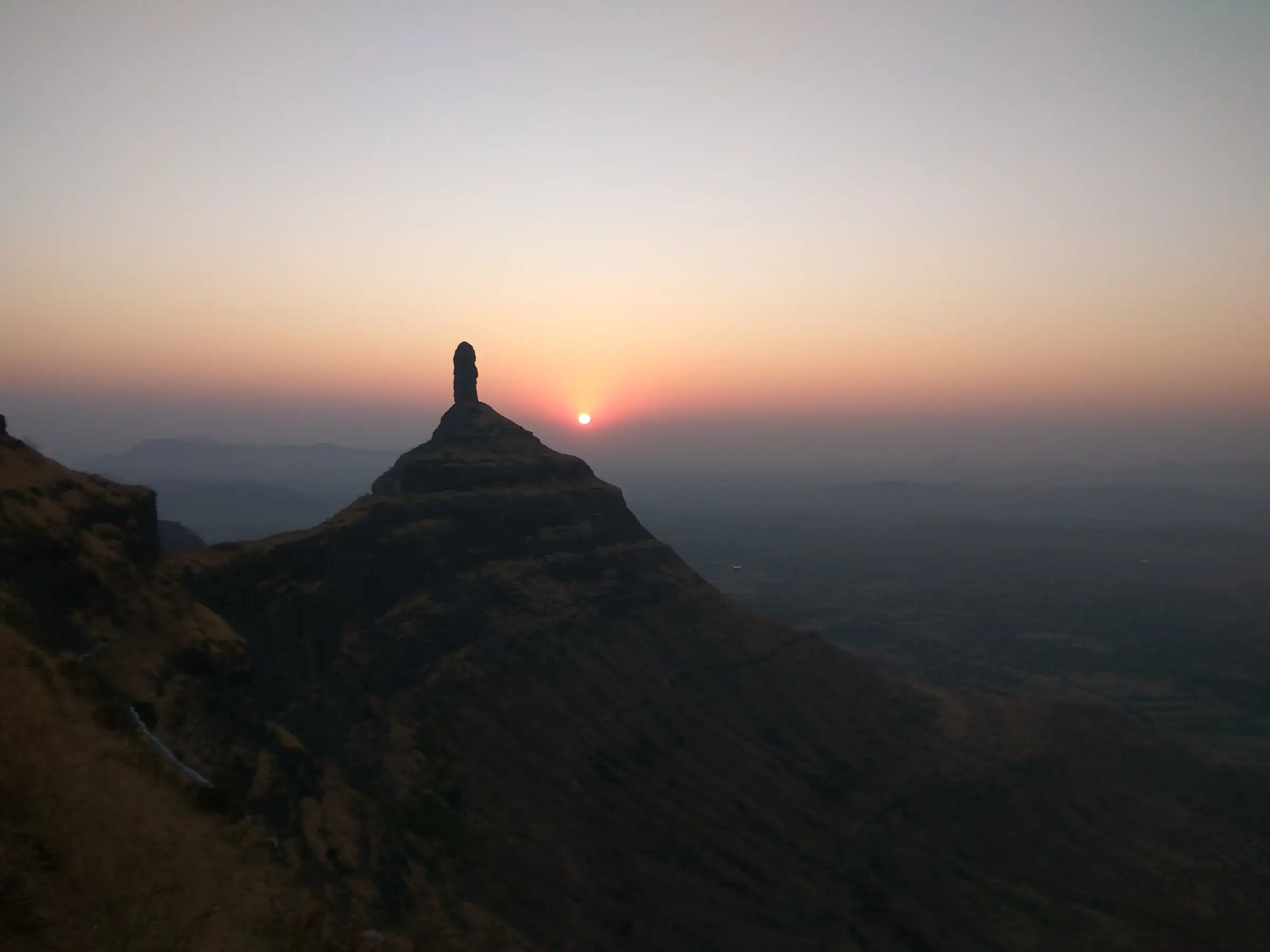 Sunrise behind the Tungi pinnacle, seen from the ridge near Mangi, with hazy plains below