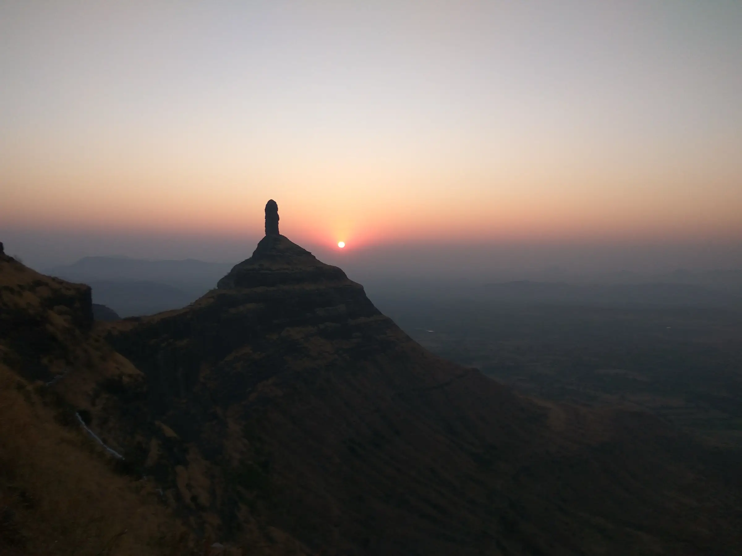 Sunrise behind the Tungi pinnacle, seen from the ridge near Mangi, with hazy plains below
