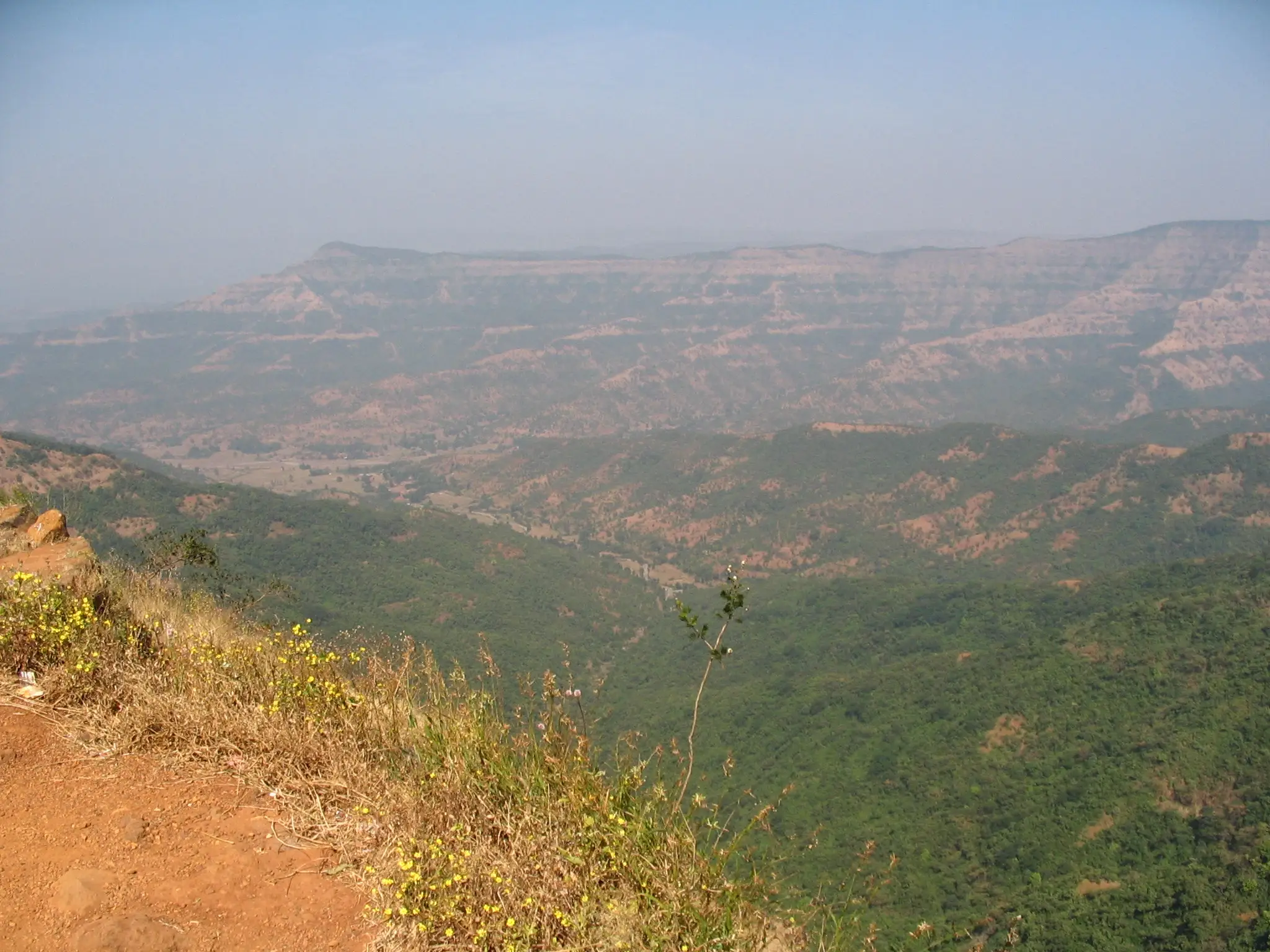 View from the edge of Vishalgad over green valleys to the layered Sahyadri plateaus